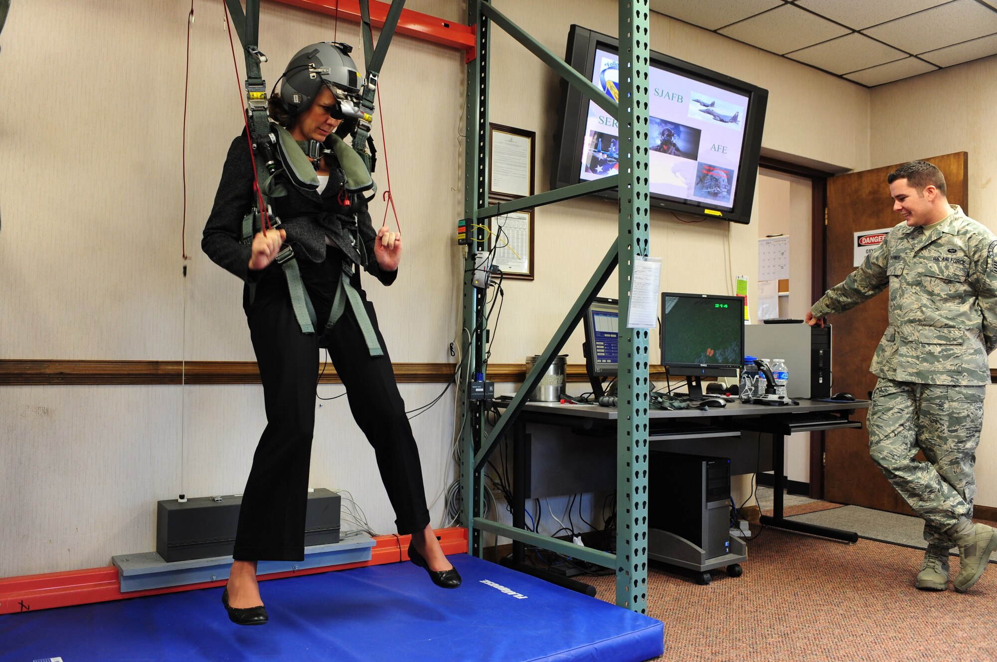 Kathy Wells takes a ride in a parachute simulator while visiting the 4th Operations Support Squadron Life Support section at Seymour Johnson Air Force Base, N.C., Jan. 13, 2012. Wells began her fall at 2,000 feet and had to glide her way to a specific spot on the ground. Staff Sgt. Justin Pishner, 4th OSS survival, evasion, resistance and escape specialist, assists Wells as she glides to the ground. Pilots and weapon systems officers receive annual training on the simulator. Wells is visiting Seymour Johnson AFB with her husband, Maj. Gen. Lawrence Wells, the 9th Air Force commander. (U.S. Air Force photo/Airman 1st Class Mariah Tolbert) 