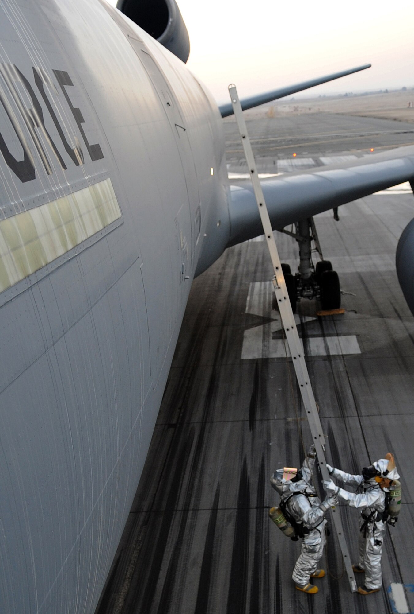 SOUTHWEST ASIA - Firefighters set up a ladder to reach the cargo door of a KC-10 Extender during a major accident response exercise at the 380th Air Expeditionary Wing Jan. 18, 2012. The exercise tested the wing?s response capabilities in the event of a plane crash. In addition, members of the host nation air force partnered with the Airmen and Soldiers, ensuring a cohesive response to a real-world emergency. (U.S. Air Force photo/Staff Sgt. J.G. Buzanowski)