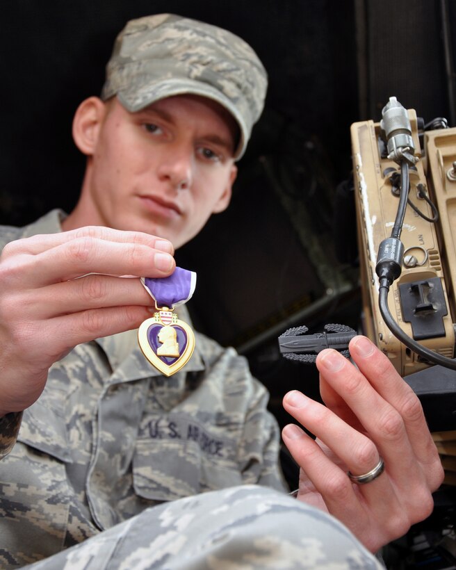 Staff Sgt. Christopher Wiedmer, 387th Expeditionary Logistics Readiness Squadron, shows his Purple Heart and Combat Action Badge in the cab of one of the trucks he drove during operations in Iraq in 2011.  Wiedmer suffered a ruptured eardrum from the concussion wave of an improvised explosive device hidden in a pile of trash outside Tikrit, Iraq. Wiedmer is 28th Logistics Readiness Squadron vehicle maintainer from Ellsworth Air Force Base, S.D. (U.S. Air Force photo/Tech. Sgt. Stacy Fowler)