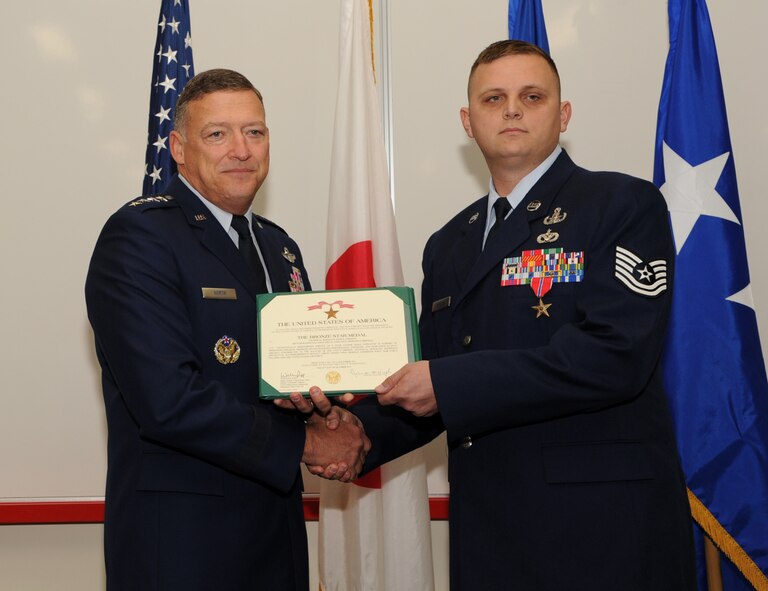 U.S. Air Force Gen. Gary North, Pacific Air Forces commander, presents U.S. Air Force Tech. Sgt. John Johnson, 18th Civil Engineer Squadron Explosive Ordnance Disposal (EOD) craftsman, with a Bronze Star Medal citation at Kadena Air Base, Japan, Jan. 9, 2012. Johnson was awarded the Bronze Star Medal for exceptionally meritorious service as an EOD Team Leader while deployed in support of Operation Enduring Freedom. (U.S. Air Force photo by Senior Airman Jarvie Z. Wallace/Released) 