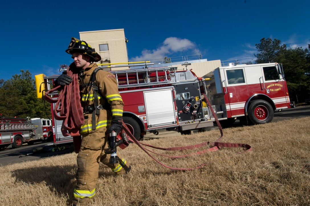 Airman 1st Class Bruce Owen, 11th Civil Engineer Squadron firefighter, extracts a fire hose from a squadron fire truck during rescue training at the Andrews burn facility Jan. 12. (Photo /Bobby Jones)