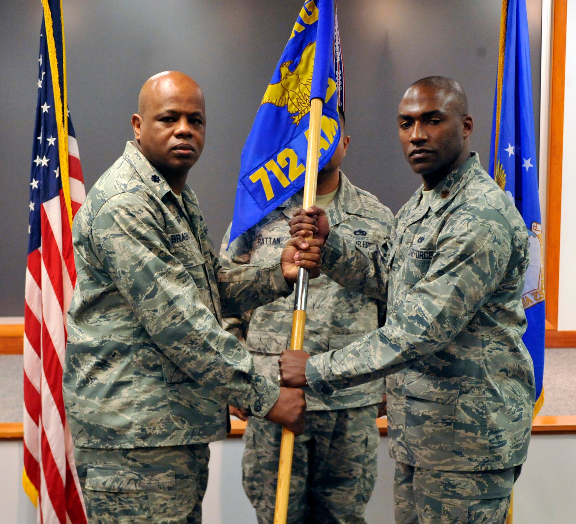 Lt. Col. Rolandrias Bradford, 512th Maintenance Group commander, passes the 712th Aircraft Maintenance Squadron guidon to Maj. Anthony Linton during an Assumption of Command Ceremony Jan. 7, 2011, in Bldg. 760's auditorium, Dover Air Force Base, Del. Linton recently served as the 436th Maintenance Operations Squadron commander. Master Sgt. Sutcliffe Rattan, 712th AMXS, served as the guidon bearer for the event. (U.S. Air Force photo by Tech. Sgt. Charles Walker)