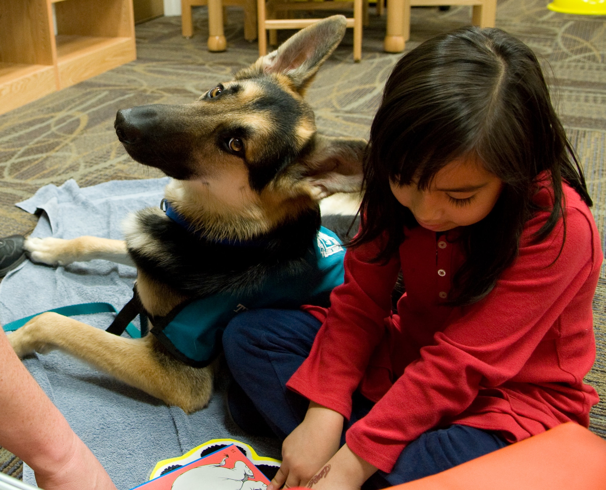 Barb Brewer, a volunteer for the Paws for Reading Program, and her dog, Toby, help Sandra Mendoza learn a new word during her reading session at the Mitchell Memorial Library, Jan. 12. The Paws for Reading program helps kids gain confidence in their reading skills. (U.S. Air Force photo/ Airman 1st Class Nicole Leidholm)