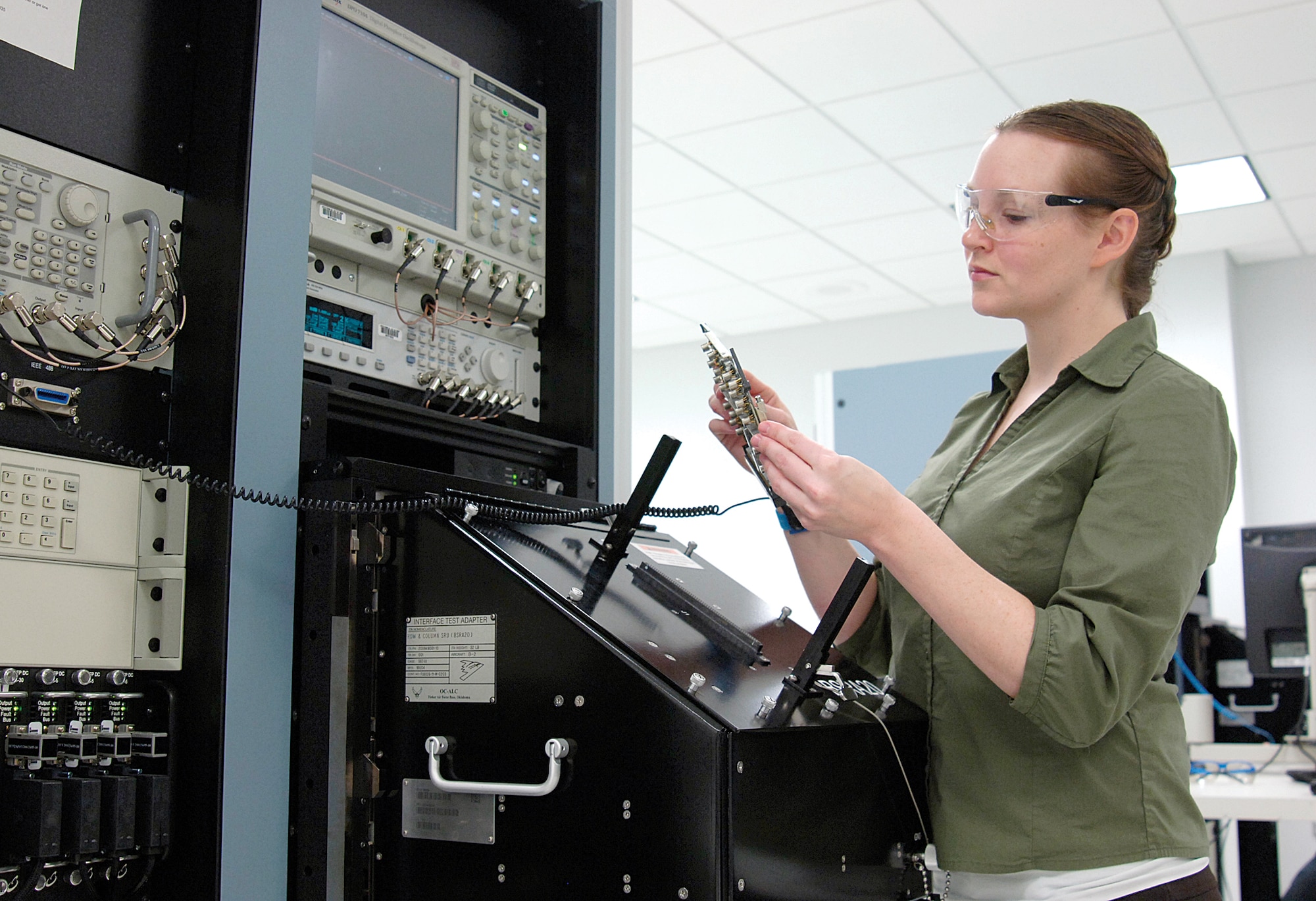 Tinker engineer Darla LeBlanc of the 559th Software Maintenance Squadron holds a B-2 Bomber circuit card at a Versatile Depot Automated Test System of the 559th Software Maintenance Squadron.  Ms. LeBlanc writes Test Program Set software for the VDATS that aids technicians in testing and fixing hundreds of B-2 Bomber circuit cards. The 559th SMXS celebrated returning the first TPS to their Tinker customer this month.  The VDATS TPS is an $82-million effort that will realize 140 sets when the project is completed in 2016. (Air Force photo by Margo Wright)