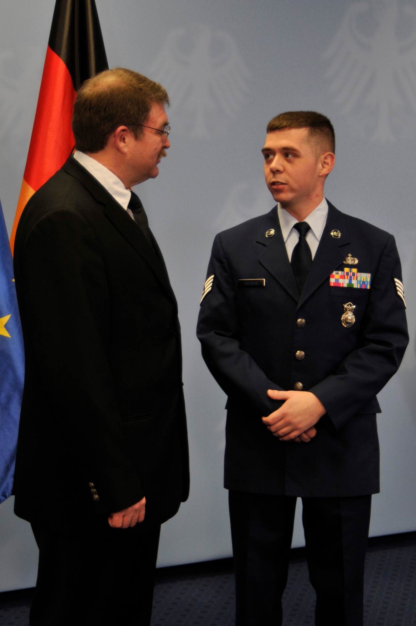 BERLIN -- Staff Sgt. Trevor Brewer, 48th Security Forces NCO in charge of vehicles, speaks with Joseph Connor at the German Ministry of the Interior Jan. 16, 2012. Both gentlemen received the Order of Merit of the Federal Republic of Germany for their actions during the March 2, 2011, shootings at Frankfurt International Airport. (U.S. Air Force photo by Staff Sgt. David Dobrydney)