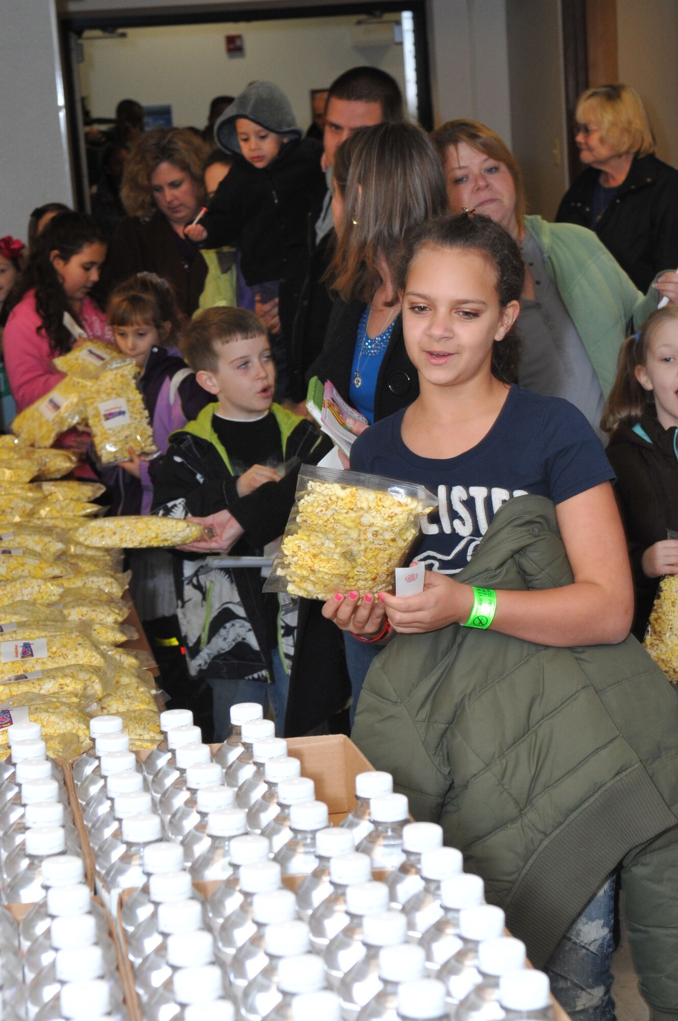 Community members are handed popcorn and glow sticks as they file into the Timmermann Center Jan. 11 for an “iCarly” screening of “iMeet the First Lady,” which features an appearance by Michelle Obama. Hundreds of servicemembers and their excited children waited outside the center, in anticipation of the cast and an exclusive screening of their newest episode. Everyone who showed up to the screening was able to get a seat. (U.S. Air Force photo by Wayne Russell/Released)