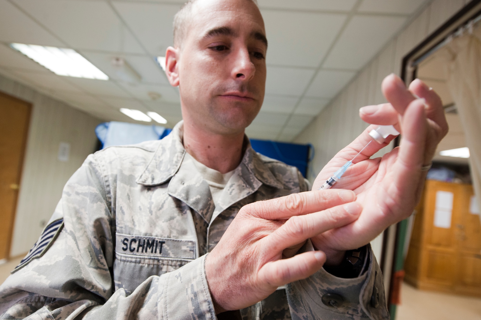 Tech. Sgt. Brian Schmit, 332nd Expeditionary Medical Group medical technician, prepares a needle prior to giving a patient an immunization shot, in an undisclosed location in Southwest Asia, Jan 19, 2012. The base medical clinic is in charge of ensuring all base personnel are up to date on their immunizations. Schmit is deployed from Spangdahlem Air Base, Germany, and is a native of Rogers Ark. (U.S. Air Force photo by Staff Sgt. Joshua J. Garcia/Released)