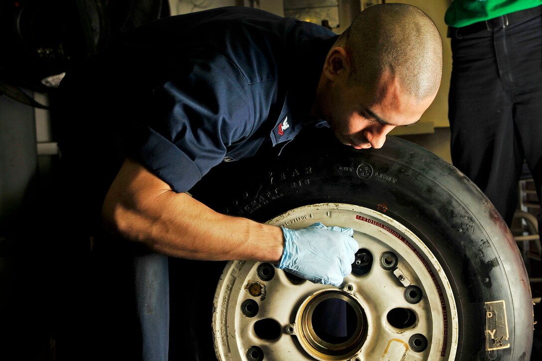 U.S. Navy Petty Officer 2nd Class Christian Samaras performs maintenance on the tire of an F/A-18C Hornet aboard the aircraft carrier USS Carl Vinson in the Arabian Sea, Jan. 12, 2012. Samaras is an aviation structural mechanic.