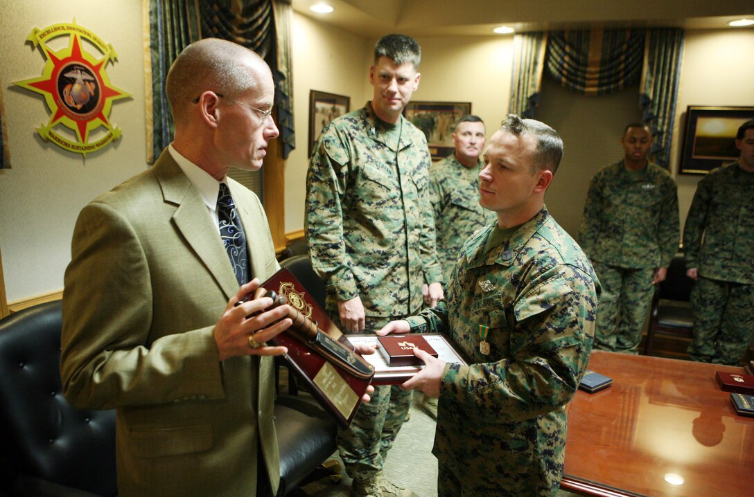 Petty Officer 1st Class Raymond R. Price, a corpsman with the Group Aid Station, 2nd Marine Logistics Group, receives an award from Kevin Jenkins, the operations manager from a local business in Jacksonville, N.C., and a retired gunnery sergeant, during a ceremony at the 2nd MLG headquarters building aboard Camp Lejeune, N.C., Jan. 20, 2012. During the ceremony Price received the 2011 2nd MLG Senior Sailor of the Year award for his outstanding achievements and performance during the past year. (U.S. Marine Corps photo by Pfc. Franklin E. Mercado)