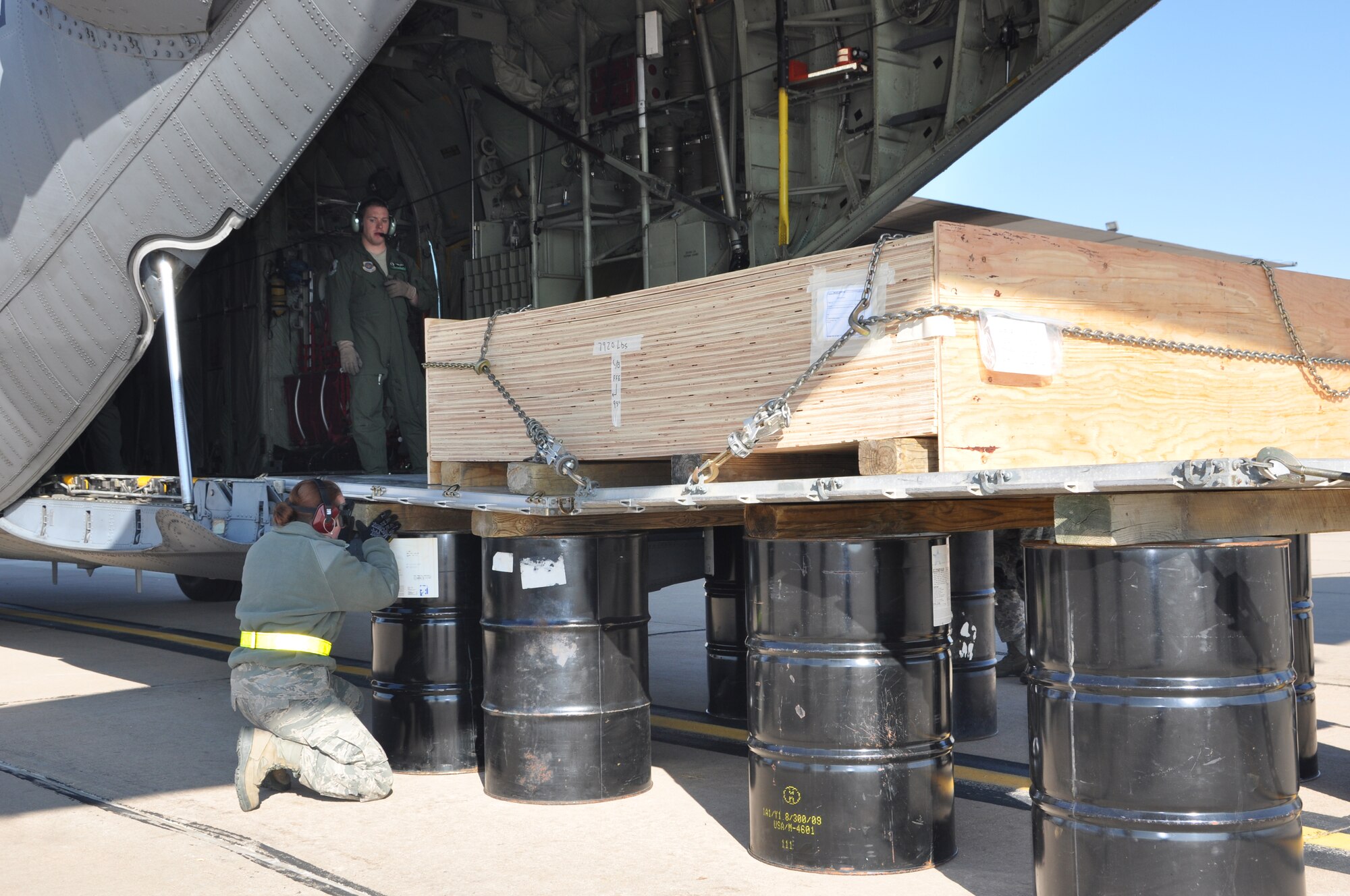 Air Force Reservist, Senior Airman Meagan Hasty an air transportation specialist assigned to the 39th Aerial Port Squadron, Peterson Air Force Base, Colo., positions a wooden beam on top of a 55 gallon drum that will support the married pallets during a “Combat Method B” offloading training exercise held at Peterson AFB, Jan 8.  This training simulates austere offloading conditions when cargo consisting of two or more pallets tied together need to be unloaded and a K-loader is not available. (U.S. Air Force photo/Tech. Sgt. Daniel Butterfield)