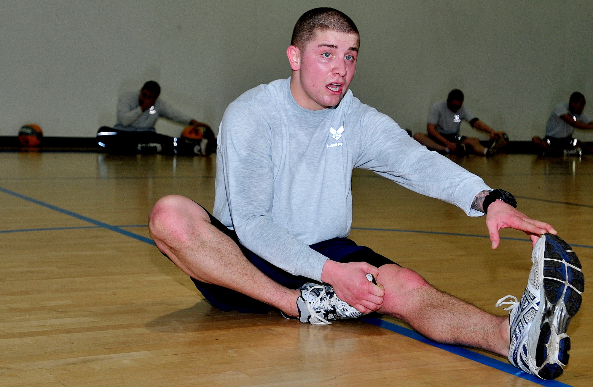 Senior Airman Steven Evans, the 48th Security Forces Squadron physical training leader, leads fellow 48th SFS members in a stretch during a cool down after their workout at Royal Air Force Lakenheath, England, Jan. 12, 2012. Since taking charge of the squadron's physical training program, the average pass rate has risen and the number of failures has decreased. (U.S. Air Force photo/Senior Airman Tiffany M. Deuel)