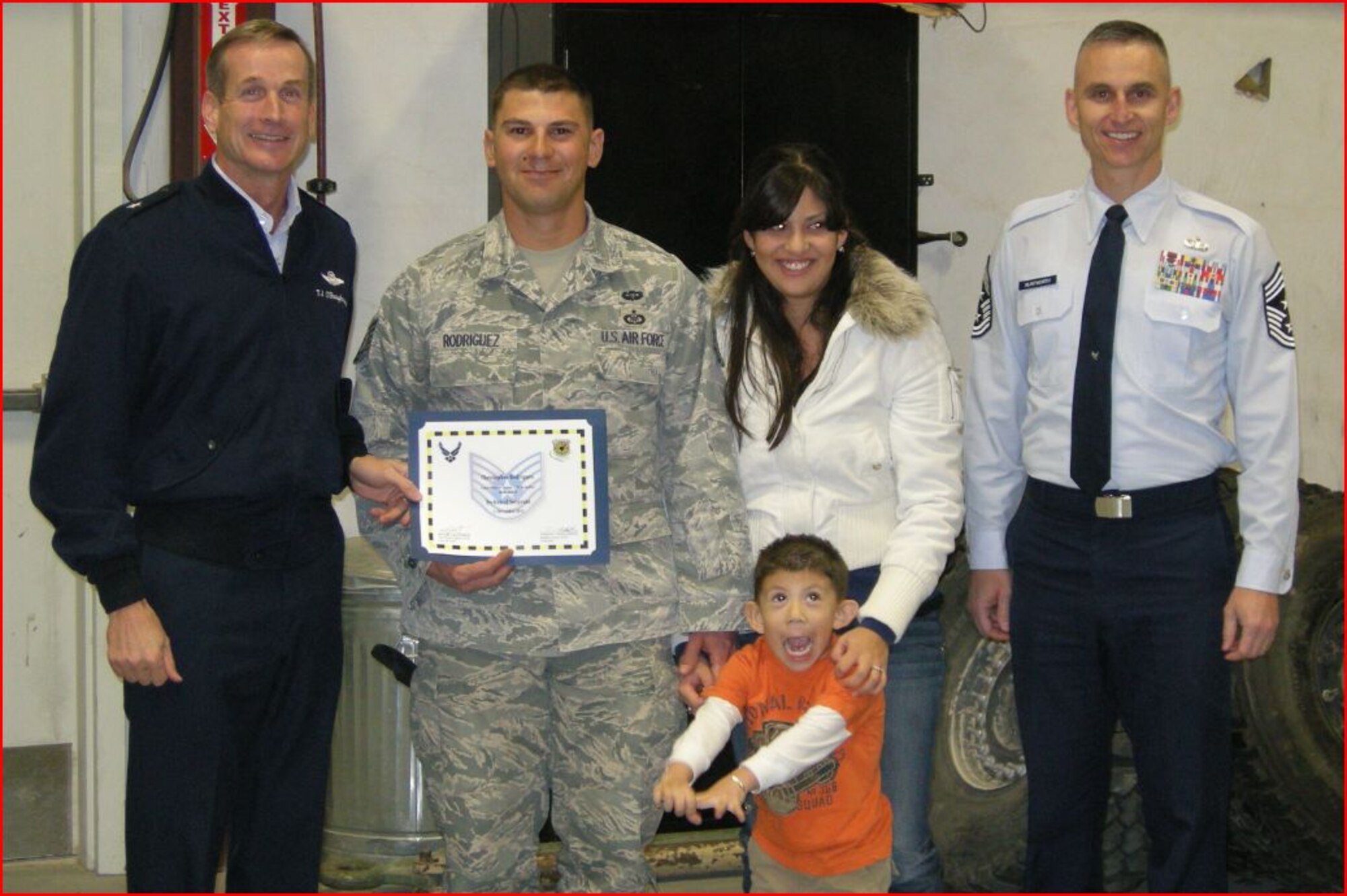 On left, Brig. Gen. Terrence O’Shaughnessy, 57th Wing commander, and, on right, Chief Master Sgt. Michael Klintworth, 57th Wing command chief, surprise Staff Sgt. Christopher Rodriguez, 12th Combat Training Squadron terminal attack controller instructor, his wife Crystal and his son Aiden with a promotion to technical sergeant under the Stripes for Exceptional Performers Program, Dec. 12, 2011, at Fort Irwin, Calif.  O’Shaughnessy and Klintworth traveled with Col. Col Stephen Waller, 57th Operations Group commander, and Chief Master Sgt. Wesley Mathias, 57th Operations Group superintendent, to present Rodriguez with his new rank. (Courtesy photo)