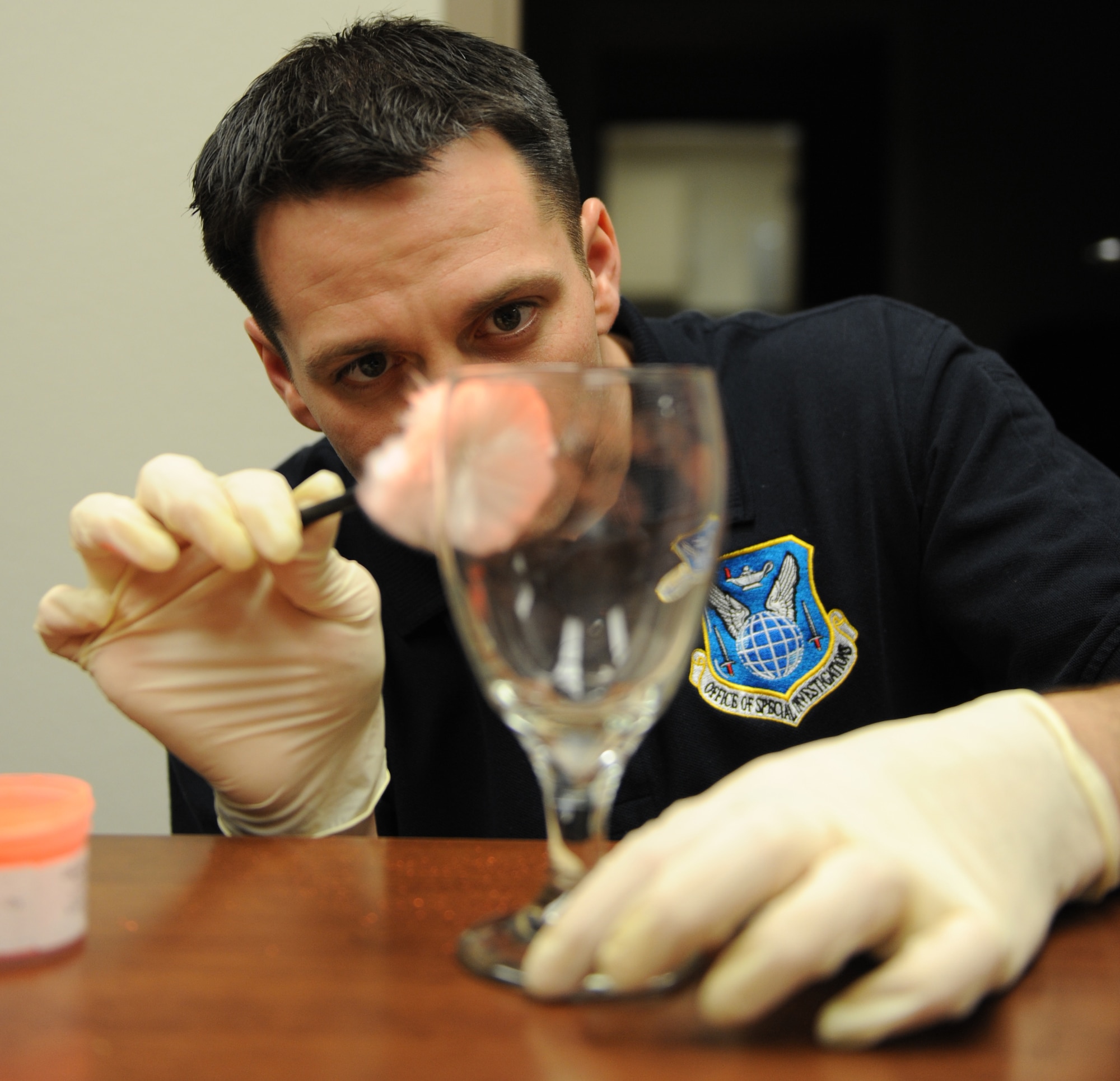 Special Agent Adam Deem, Air Force Office of Special Investigation Detachment 219, dusts a glass for fingerprints at Barksdale Air Force Base, La., Jan. 18. Dusting for finger prints involves dusting with fine particles of the powder to adhere to residue left by skin from palms, fingers and feet. (U.S. Air Force photo/Airman 1st Class Micaiah Anthony)(RELEASED)
