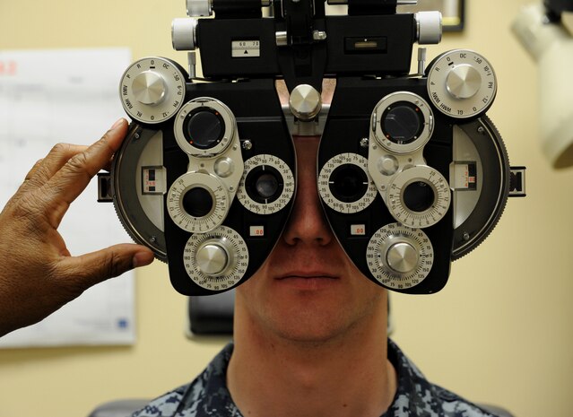 Fireman Ethan Rooney undergoes a routine eye exam from Certified Opthalmic Technician Johnny Knight Sr. Jan. 17 at Naval Health Clinic Charleston. The device used is a Phoropter, which measures the refractive error to determine an individual's spectacle prescription. Rooney is  astudent  at the Naval Nuclear Power Training Command at Joint Base Charleston- Weapons Station. (U.S. Air Force photo/Airman First Class Ashlee Galloway)