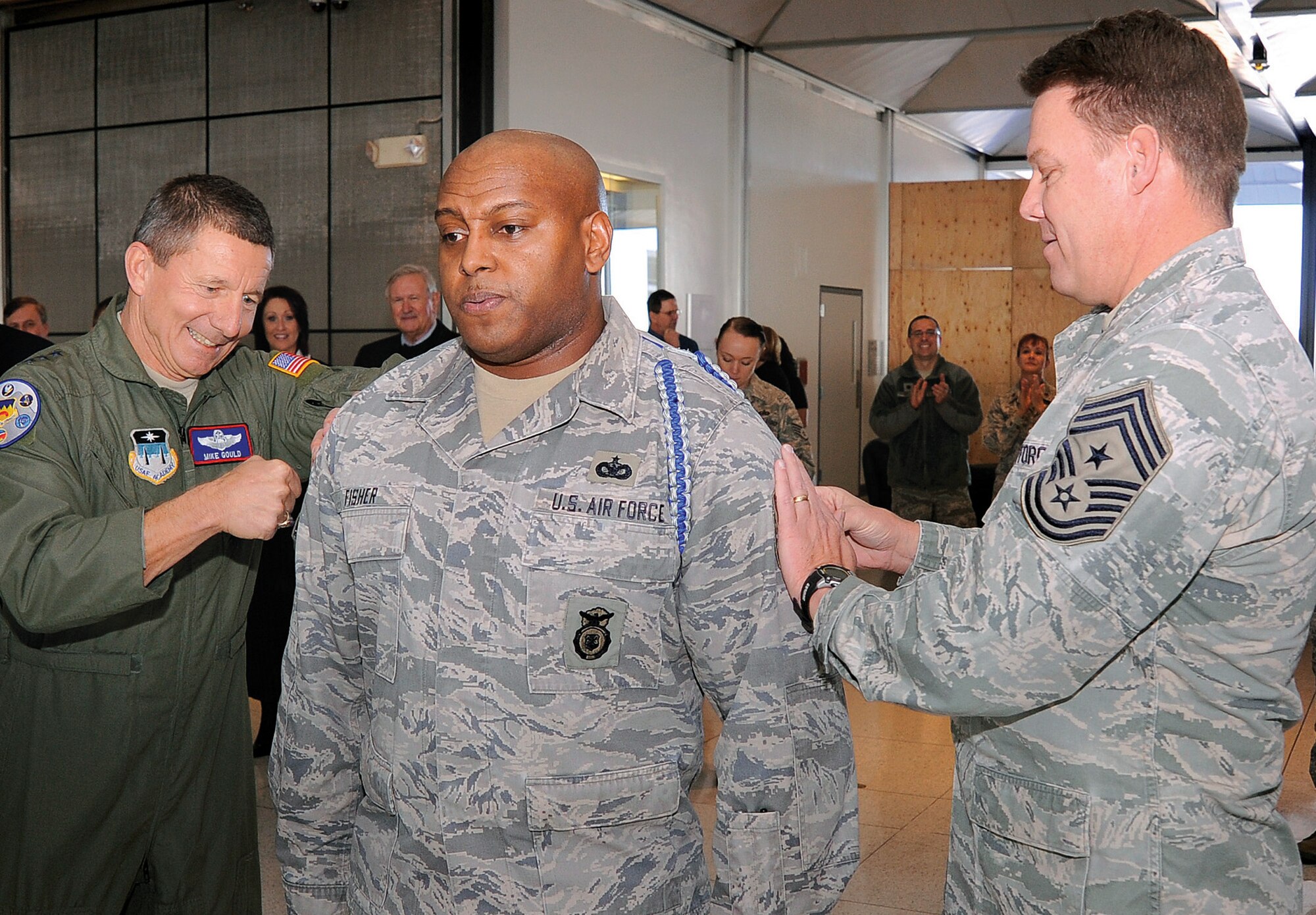 Lt. Gen. Mike Gould, Academy superintendent, and Chief Master Sgt. Todd Salzman, Academy command chief, surprise Master Sgt. Christopher Fisher with a STEP promotion Tuesday at Mitchell Hall. Fisher is the NCO in charge of drill and ceremonies for the Commandant of Cadets. (U.S. Air Force Photo/Mike Kaplan)