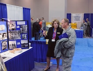 Col. Scott Peel, 902nd Mission Support Group commander, and Lillian E. Nolan, Air Education Training Command historian, discuss Joint Base San Antonio history at the AETC history office display at the Air Education Training Command 2012 Symposium held in San Antonio, Texas, Jan. 12 - 13.  (U.S. Air Force photo by Don Lindsey)