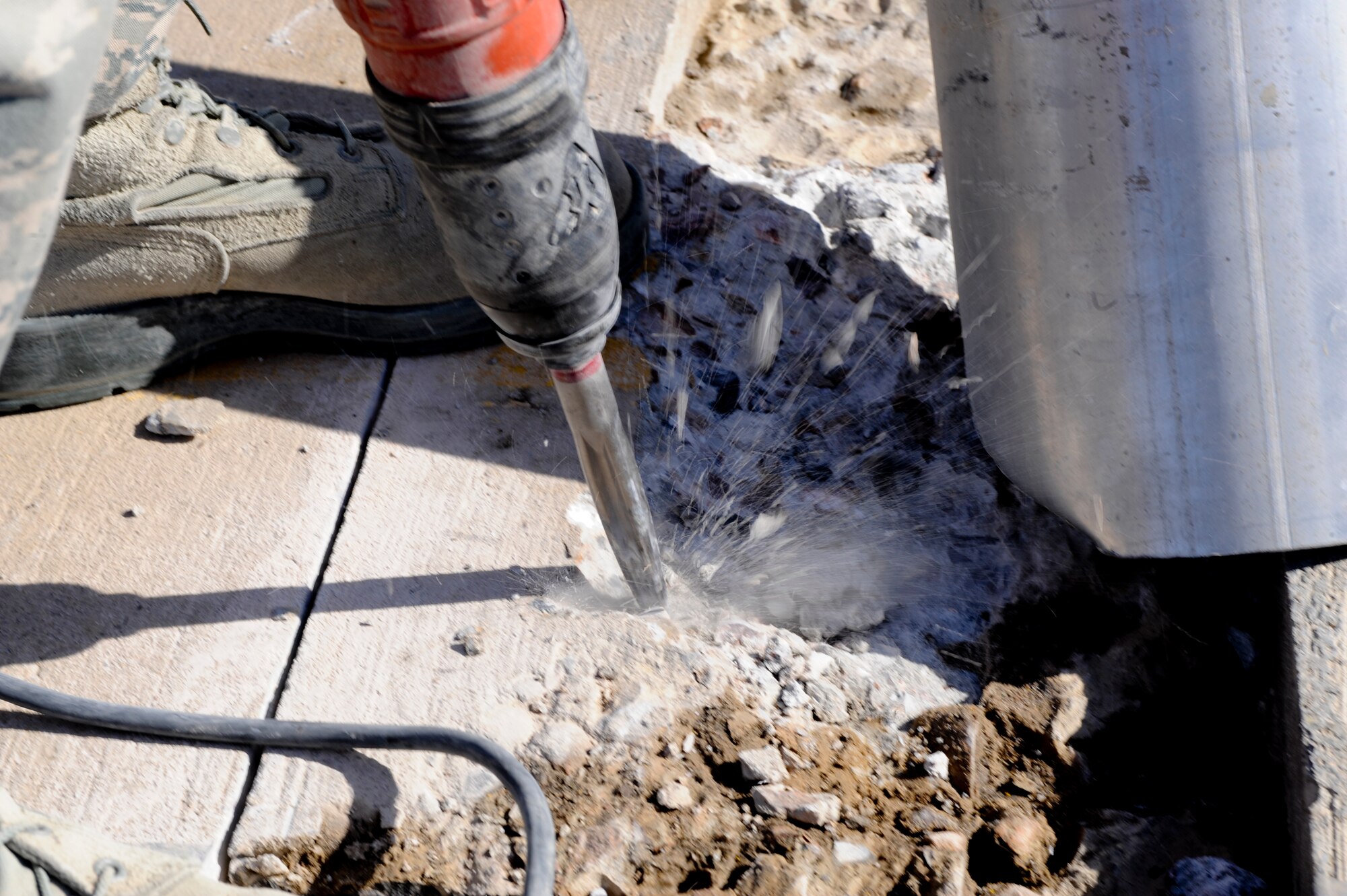 Pieces of the runway fly as a hammer drill breaks up cement at undisclosed location in Southwest Asia, Jan. 20, 2012. The 332nd Expeditionary Civil Engineer Squadron's heavy equipment shop was tasked to make repairs to certain areas of the runway. The process took about four hours before the area was cleared for use. (U.S. Air Force photo by Staff Sgt. Joshua J. Garcia/Released)