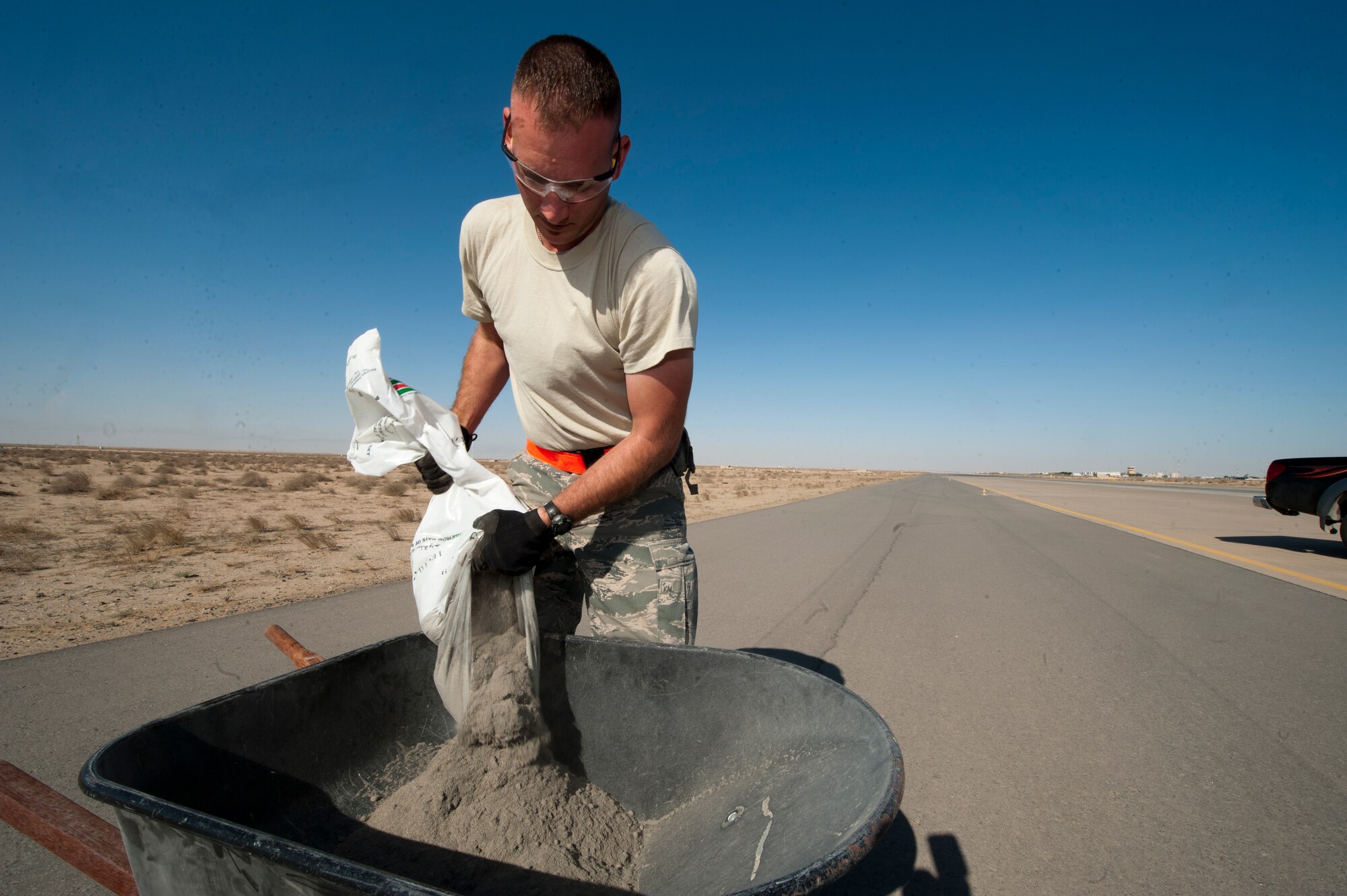 Staff Sgt. Matthew Sywassink, 332nd Expeditionary Civil Engineer Squadron heavy equipment operator, prepares quick dry cement prior to pouring it onto the flightline at an undisclosed location in Southwest Asia, Jan. 20, 2012. The cement is being used to repair the host nation's runway. Sywassink is native to New Boston, Ill., and is deployed from Davis-Monthan Air Force Base, Ariz. (U.S. Air Force photo by Staff Sgt. Joshua J. Garcia/Released)