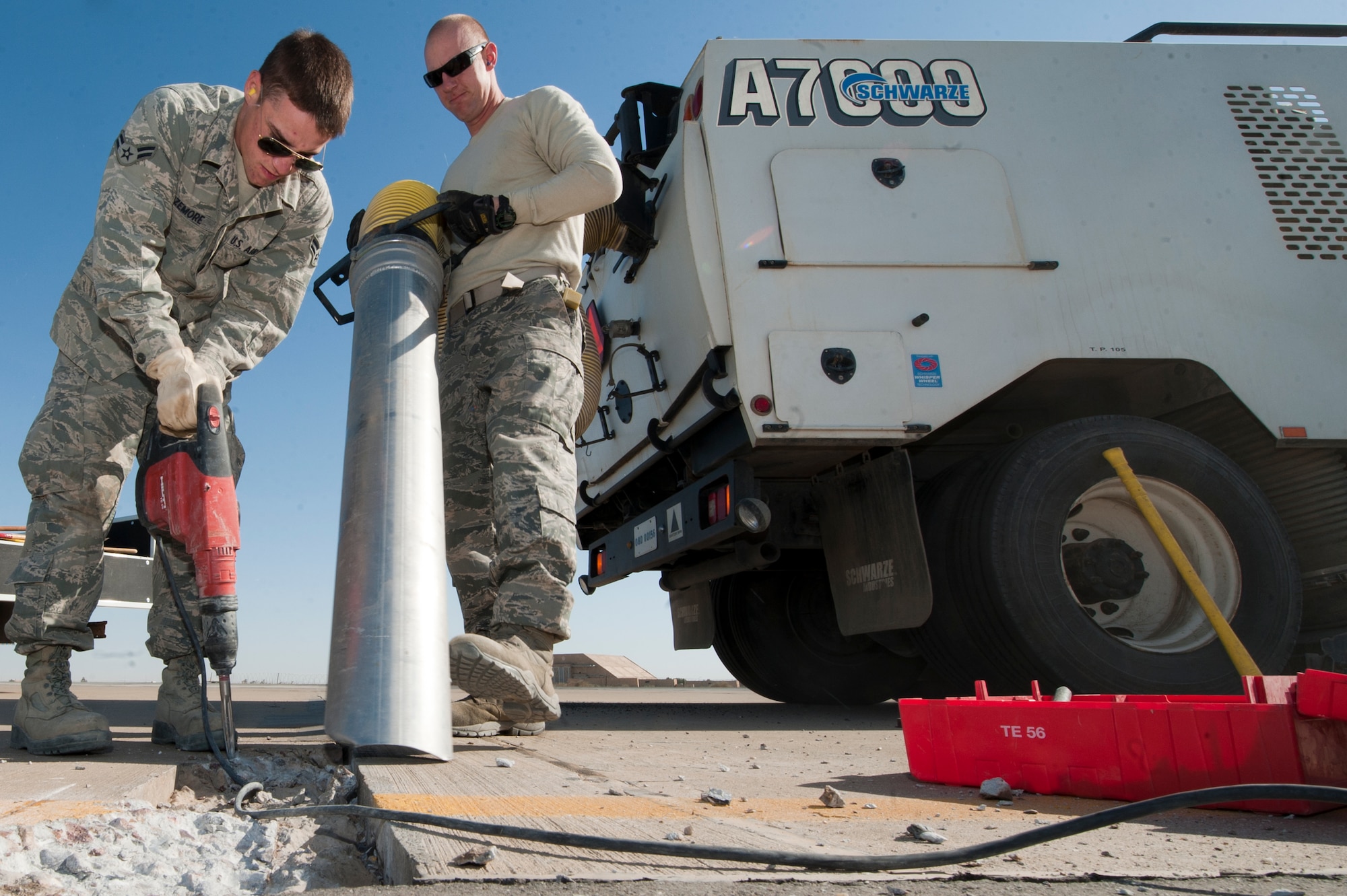 Airman 1st Class Derek Sizemore, loosens asphalt as Staff Sgt. Matthew Detzel, collects the debris during a flightline repair job at an undisclosed location in Southwest Asia, Jan. 20, 2012. Both are 332nd Expeditionary Civil Engineer Squadron heavy equipment operators. Sizemore is native to Hattiesburg, Miss. and deployed from Whiteman Air Force Base, Mo., and Detzel is native to St. Louis, Mo., and is deployed from Scott Air Force Base, Ill. (U.S. Air Force photo by Staff Sgt. Joshua J. Garcia/Released)