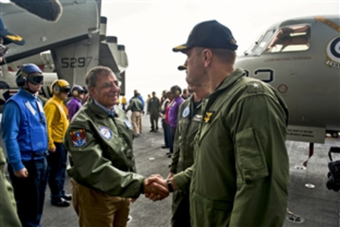 Defense Secretary Leon E. Panetta shakes hands with Navy Rear Adm. Dennis E. FitzPatrick, commander of Strike Force Training Atlantic, upon arrival aboard the aircraft carrier USS Enterprise in the Atlantic Ocean, Jan. 21, 2012.