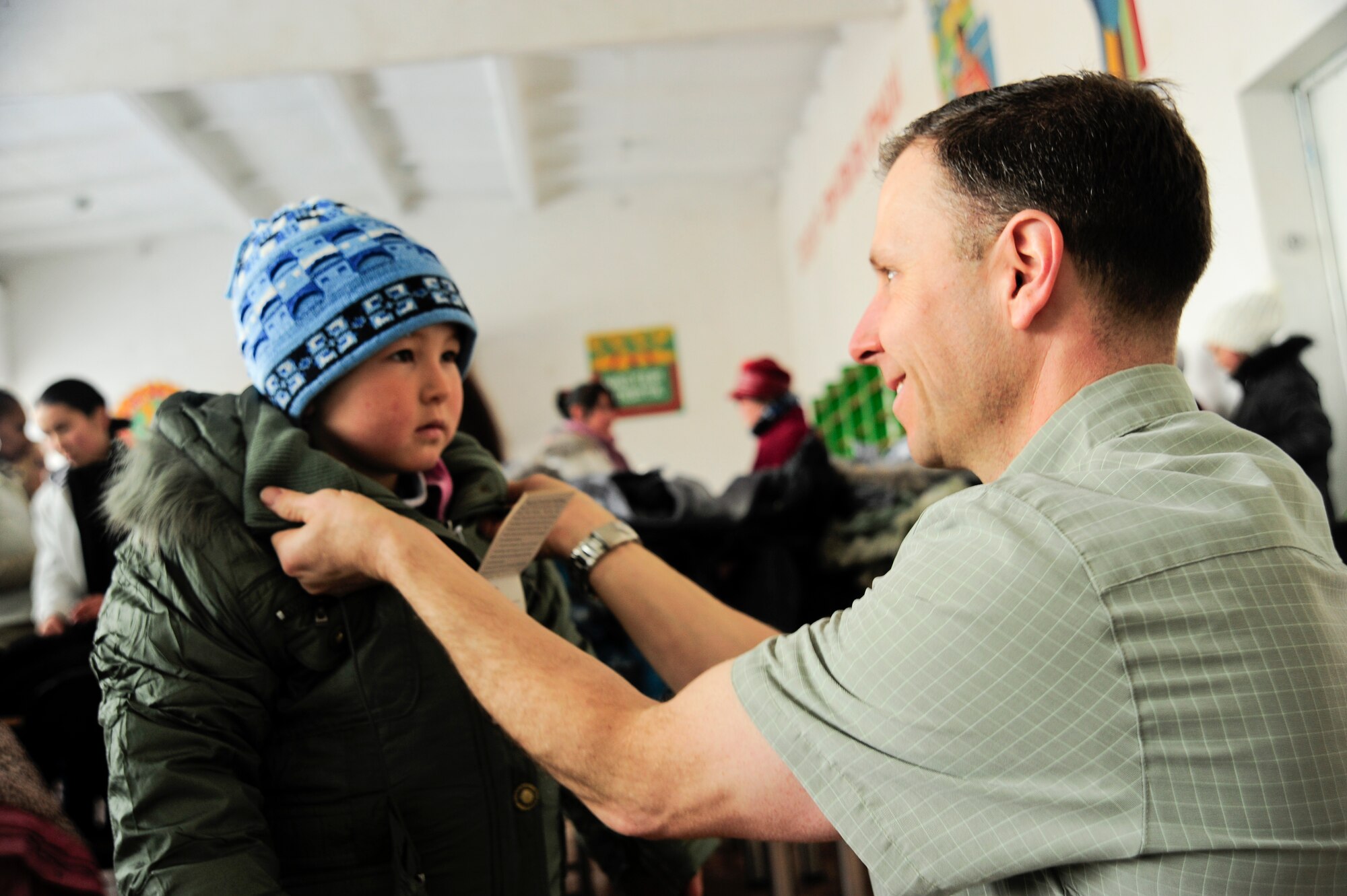 Senior Master Sgt. Mark Redden fits a Kyrgyz child with a new coat Jan. 16, 2012, during an Operation Warm and Dry distribution at Emgekchil School in Sary-Oi, Kyrgyzstan. The distribution of winter coats and blankets was conducted during a five-day mission to the Issyk-Kul region of Kyrgyzstan. Redden is the superintendent of the 376th Air Expeditionary Wing Theater Security Cooperation division deployed here from Scott Air Force Base, Ill. (U.S. Air Force Photo/Staff Sgt. Angela Ruiz)