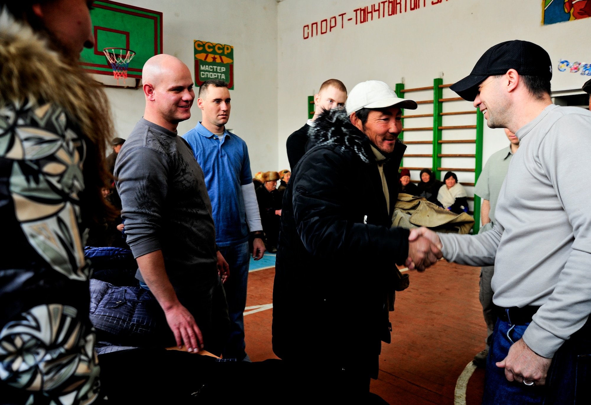 Egenberdiy Gasiev shakes Capt. Steve Martin’s hand Jan. 16, 2012, after receiving a new coat during an Operation Warm and Dry distributio,n while Staff Sgt. Shane Goss and other Airmen of the 376th Air Expeditionary Wing watch at the Emgekchil School in Sary-Oi, Kyrgyzstan. More than 50 Airmen from the 376th AEW volunteered their time to assist in the distribution of winter coats and blankets in the Issyk-Kul region of Kyrgyzstan. Martin is the 376th AEW Theater Security Cooperation division’s medical director and the Issyk-Kul mission trip leader. He is deployed to the Transit Center from Davis-Monthan Air Force Base, Ariz. Goss is a readiness and emergency management journeyman with the 376th Expeditionary Civil Engineer Squadron deployed here from Eglin AFB, Fla. (U.S. Air Force Photo/Staff Sgt. Angela Ruiz)