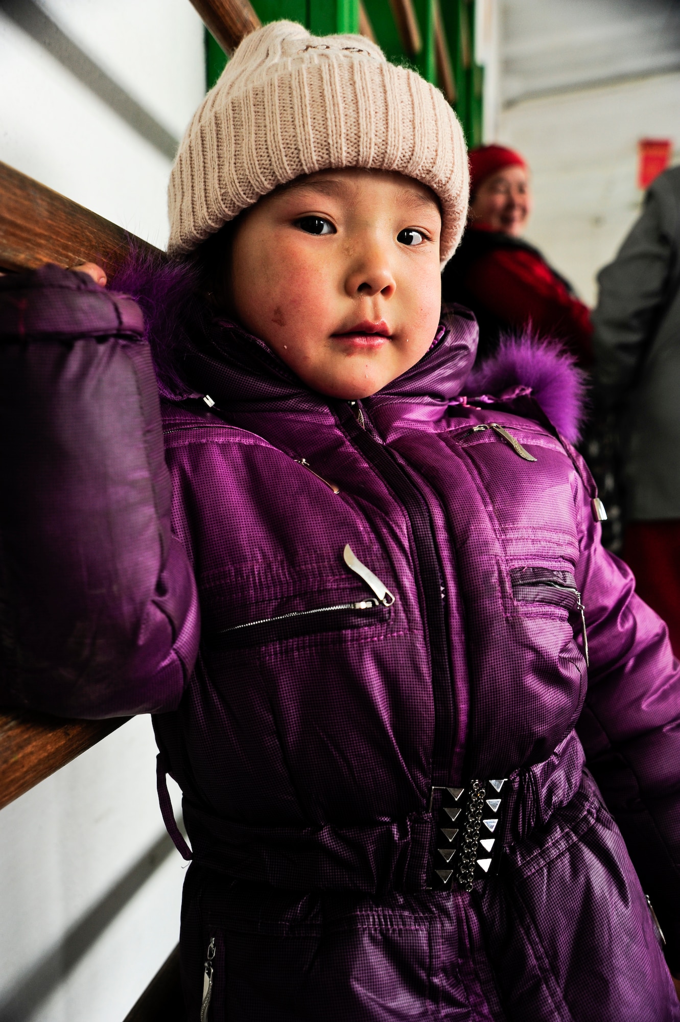 Aynura Bsekieva, wearing her new coat, leans against a wall in the Emgekchil School gymnasium in Sary-Oi, Kyrgyzstan, during an Operation Warm and Dry distribution Jan. 16, 2012. The distribution was conducted during a five-day mission to the Issyk-Kul region of Kyrgyzstan, and more than 50 Airmen from the 376th Air Expeditionary Wing volunteered their time. There are seven phases to the Warm and Dry mission and this is the halfway point and the fourth phase for the distributions. (U.S. Air Force Photo/Staff Sgt. Angela Ruiz)
