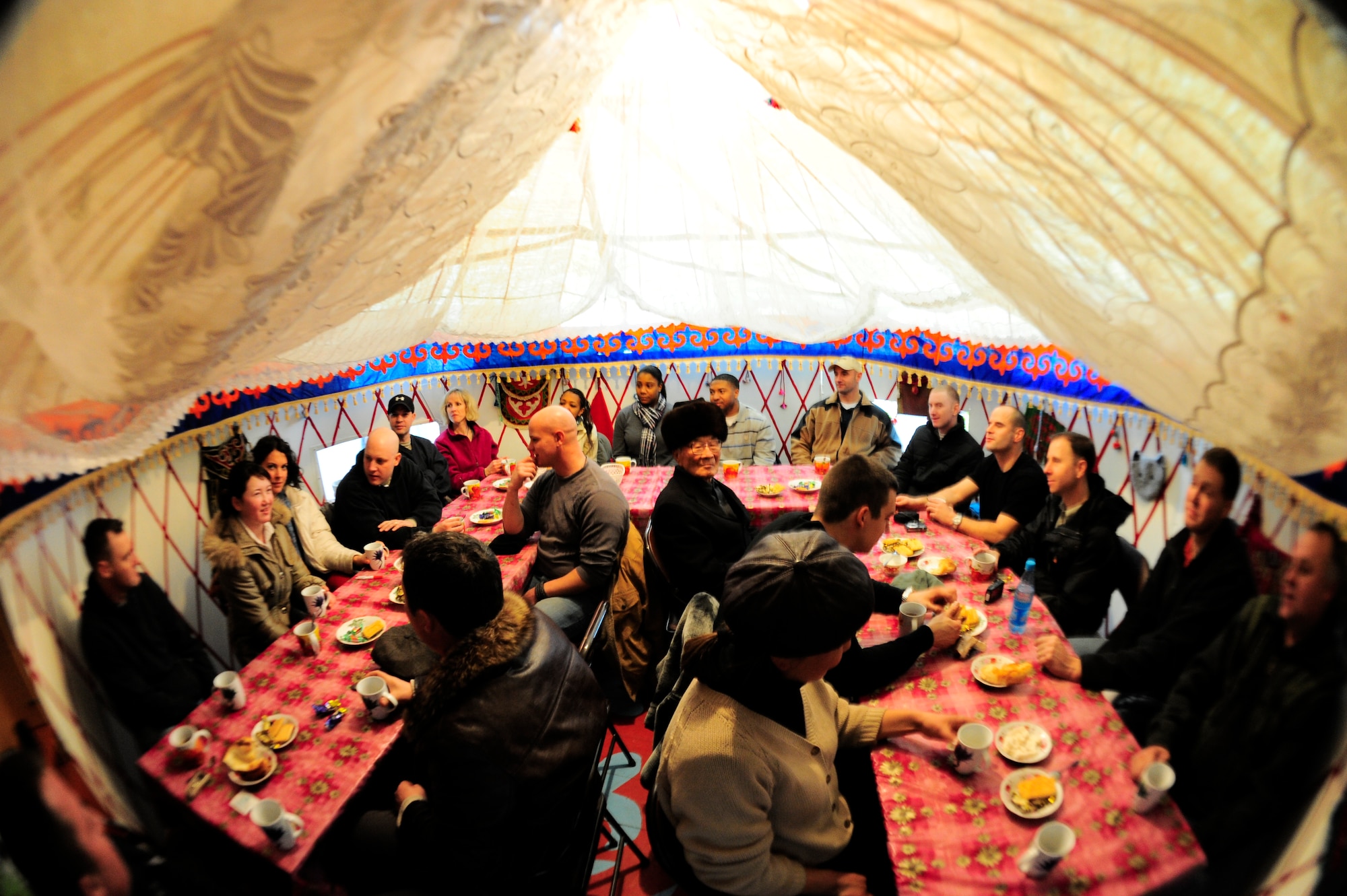 Airmen of the 376th Air Expeditionary Wing and Kyrgyz citizens sit inside a yurt at the Emgekchil School for tea and cookies Jan. 16, 2012, after an Operation Warm and Dry distribution in Sary-Oi, Kyrgyzstan. A yurt is a traditional tent made of felt, mats and carpets, with a fireplace located in the center and interior walls decorated with straw mats.(U.S. Air Force Photo/Staff Sgt. Angela Ruiz)