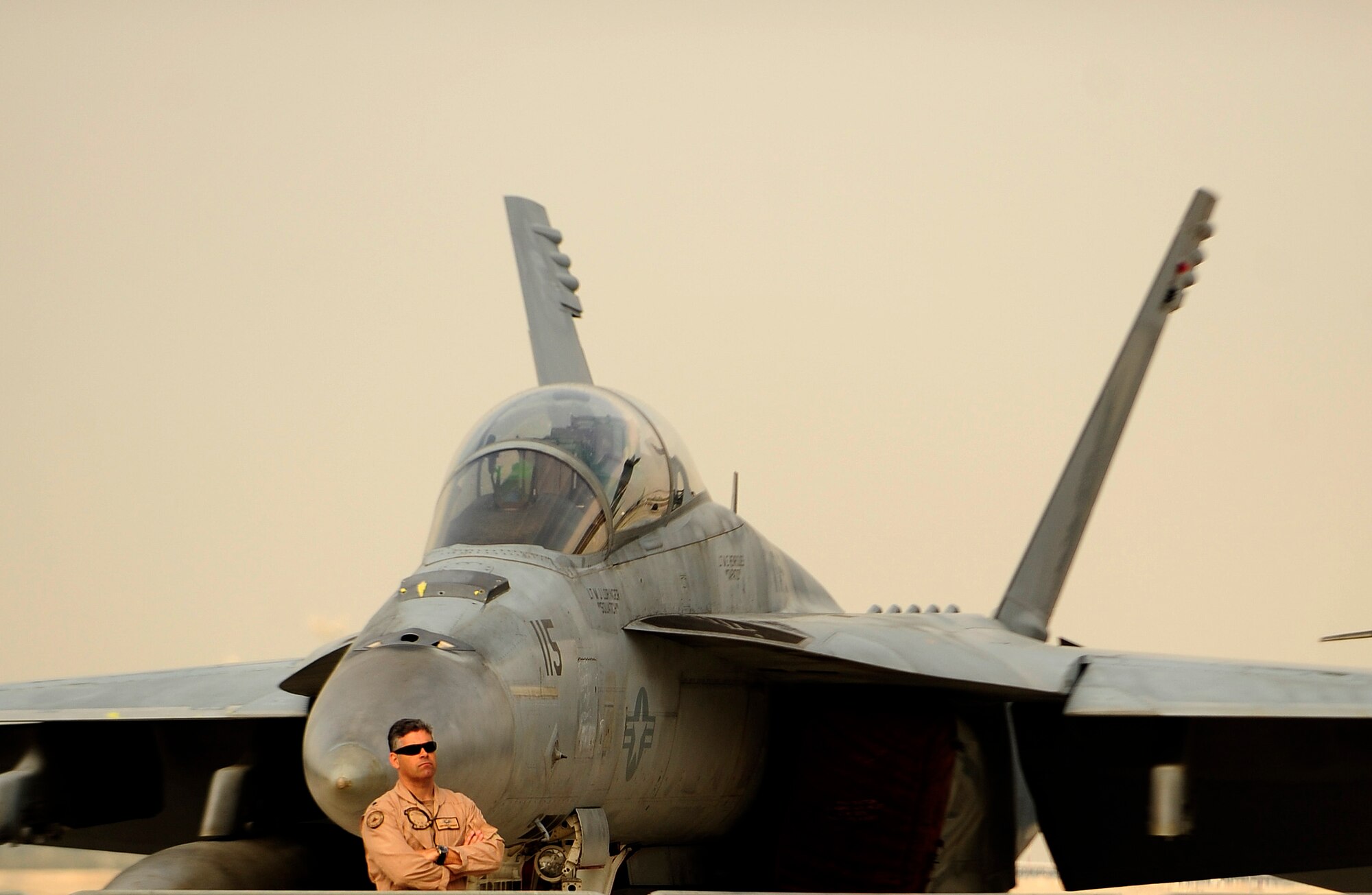 A member of the U.S. Navy stands in front of an F-18 Super Hornet aircraft while on static display at the Bahrain International Airshow 2012 at Shakir Air Base, Bahrain Jan. 19, 2012. This event strengthens partnerships in the region and allows the United States and coalition and partner nations, work together to promote security, stability and mutual interests in the region. The U.S. Air Force showcased a variety of military aircraft through static displays, including the C-17 Globemaster III, C-130H Hercules, and F-15E Strike Eagle. Additionally, a large number of aircrew and support personnel from bases in Southwest Asia, Europe, and the United States were available to answer questions about the aircraft technology and capabilities. (U.S. Air Force photo by Staff Sgt. Andy M. Kin)   