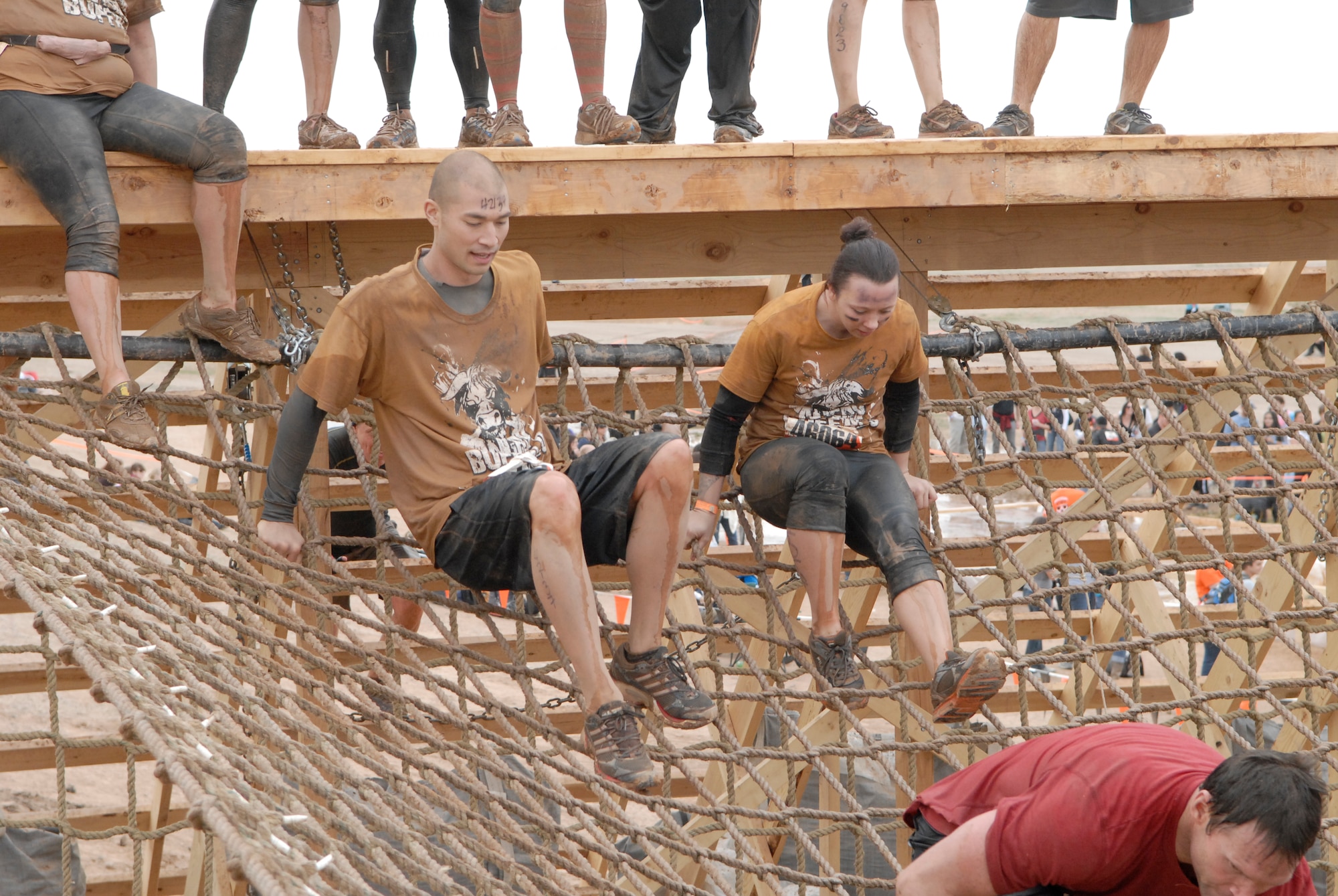 Tech. Sgt. John Knighten, 412th Maintenance Squadron electronics section supervisor, Edwards Air Force Base, Calif., left, and Staff Sgt. Patricia Radomski, 310th Aircraft Maintenance Unit, Luke Air Force Base, Ariz., climb down a rope ladder in the Tough Mudder Jan. 14 at the Mesa Proving Grounds in Mesa, Ariz. (U.S. Air Force photo by Airman 1st Class David Owsianka)