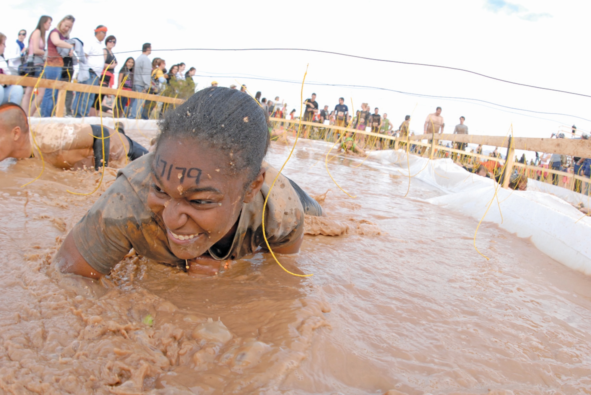 Senior Airman Danielle Sturdivant, 56th Communications Squadron, Luke Air Force Base, Ariz., crawls through the electric eel obstacle Jan. 14 during the Tough Mudder at the Mesa Proving Grounds in Mesa, Ariz. The yellow wires contained electricity and would shock the person when they touched it. (U.S. Air Force photo by Airman 1st Class David Owsianka)