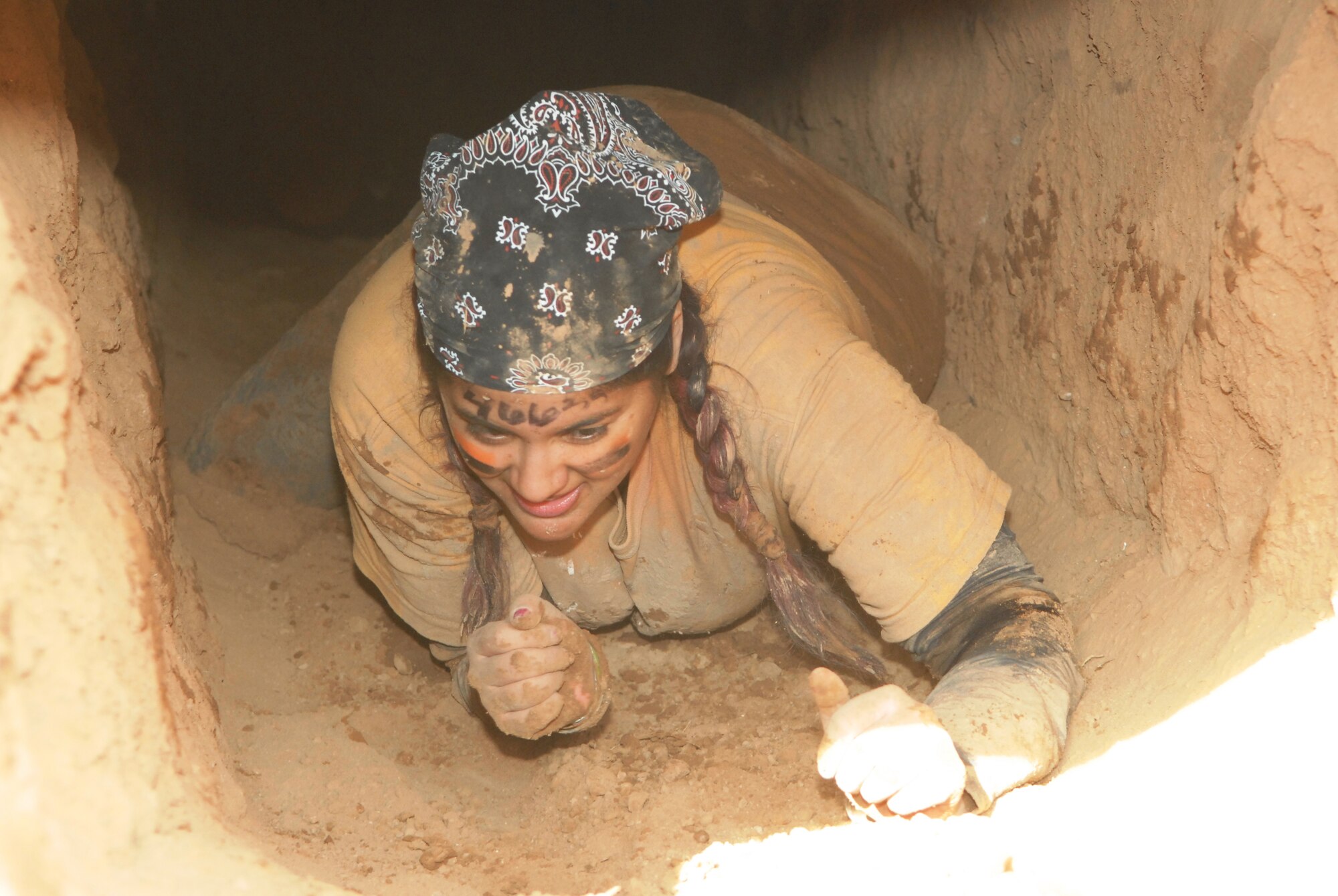 Jessica Saldana, Luke Air Force Base, Ariz., low crawls through the Tough Mudder dirty holes obstacle Jan. 14 at the Mesa Proving Grounds in Mesa, Ariz. (U.S. Air Force photo by Airman 1st Class David Owsianka)