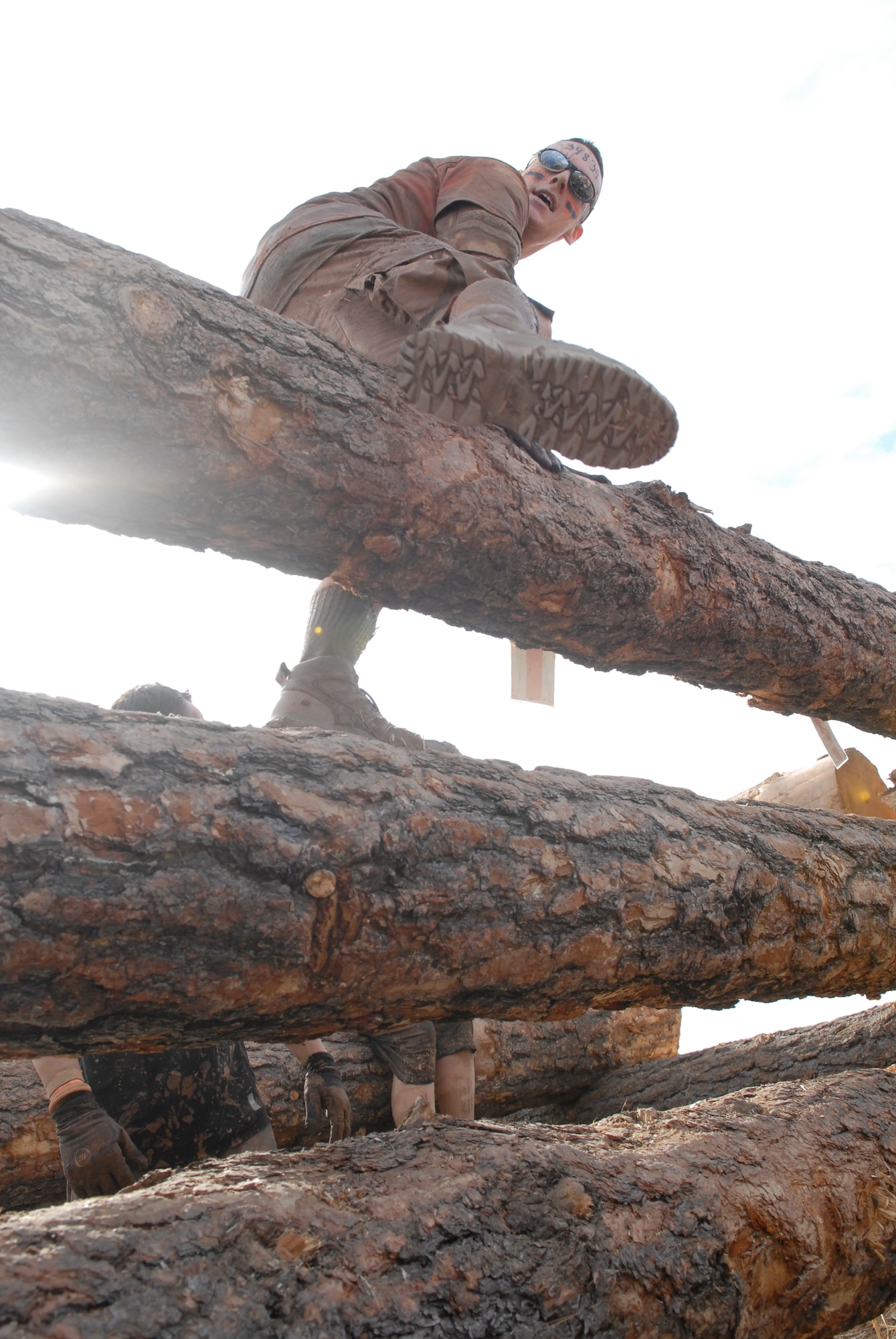 Tech. Sgt.  Joey Crowell, Area Defense Counsel paralegal, Luke Air Force Base, Ariz., climbs over logs during the Tough Mudder log jamming obstacle Jan. 14 at the Mesa Proving Grounds in Mesa, Ariz. (U.S. Air Force photo by Airman 1st Class David Owsianka)
