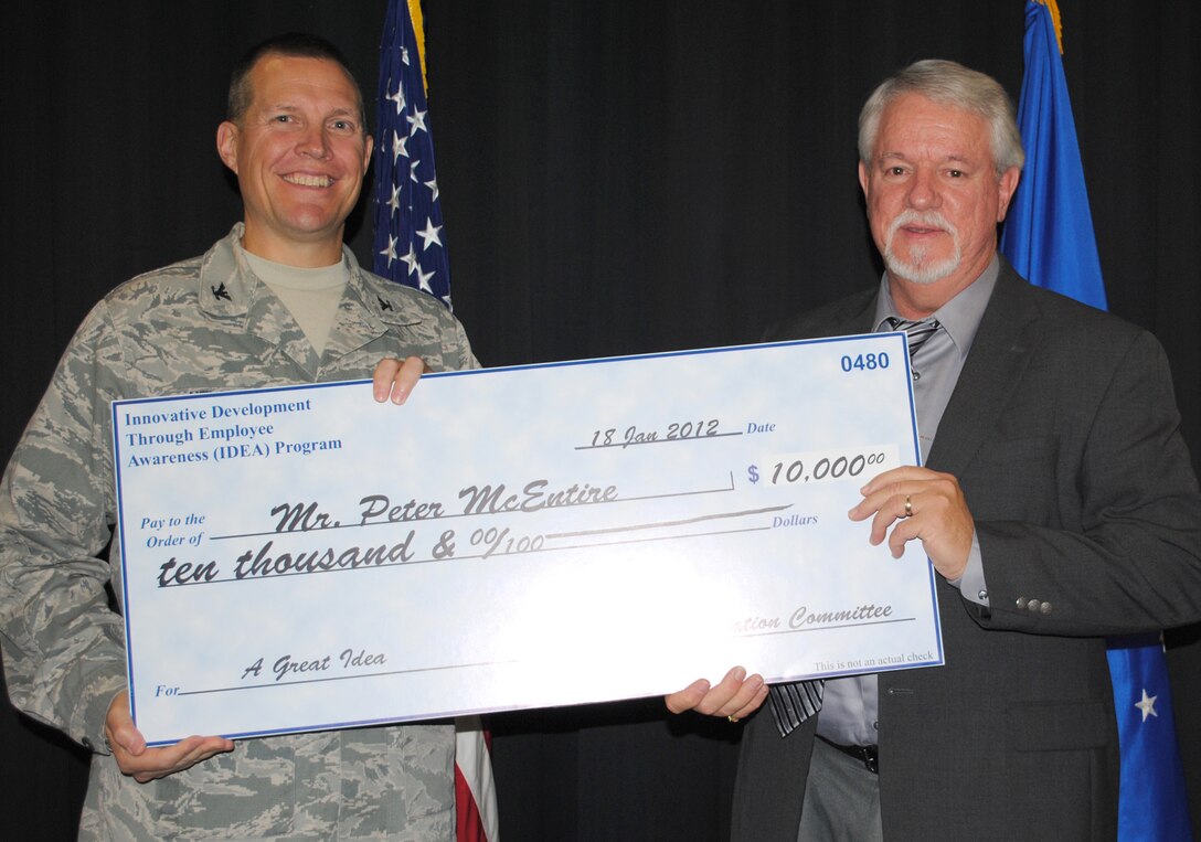 Col. Paul Nelson, 480th Intelligence, Surveillance and Reconnaissance Wing commander, presents a $10,000 check to Peter McEntire for the Air Force Innovative Development through Employee Awareness Program Jan. 18, 2012. McEntire, 480th ISR systems integration chief, designed and built a metal, separation shield for junction boxes to house classified and unclassified fibers, saving the Air Force more than half a million dollars annually. (U.S. Air Force photo by Marge McGlinn/Released)