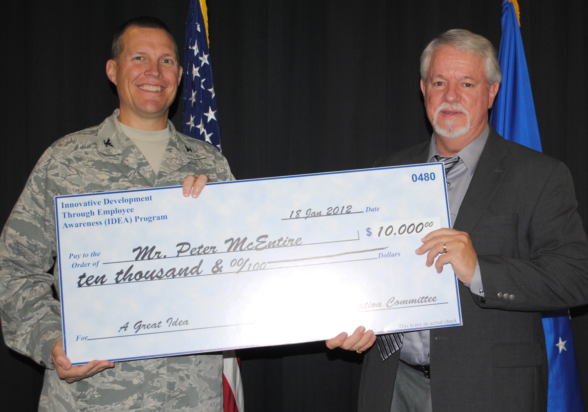 Col. Paul Nelson, 480th Intelligence, Surveillance and Reconnaissance Wing commander, presents a $10,000 check to Peter McEntire for the Air Force Innovative Development through Employee Awareness Program Jan. 18, 2012. McEntire, 480th ISR systems integration chief, designed and built a metal, separation shield for junction boxes to house classified and unclassified fibers, saving the Air Force more than half a million dollars annually. (U.S. Air Force photo by Marge McGlinn/Released)