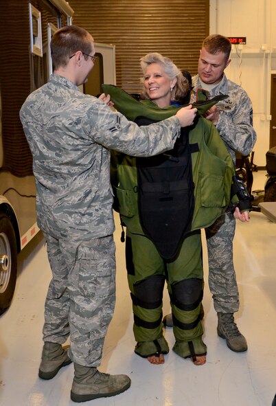 Kathy Wells, wife of 9th Air Force Commander Maj. Gen. Lawrence Wells, tries on an EOD 9 Bomb Suit with help from Senior Master Sgt. John Bell, 116th Civil Engineering Squadron explosive ordinance disposal (EOD) technician, right, and Airman 1st Class Mark Morrissey, 461st Aircraft Maintenance Squadron, Robins Air Force Base, Ga., Jan. 18, 2012.  Wells visited the EOD shop during a two-day trip to the 116th and 416st Air Control Wings with her husband.   (Air National Guard photo by Master Sgt. Roger Parsons/Released)