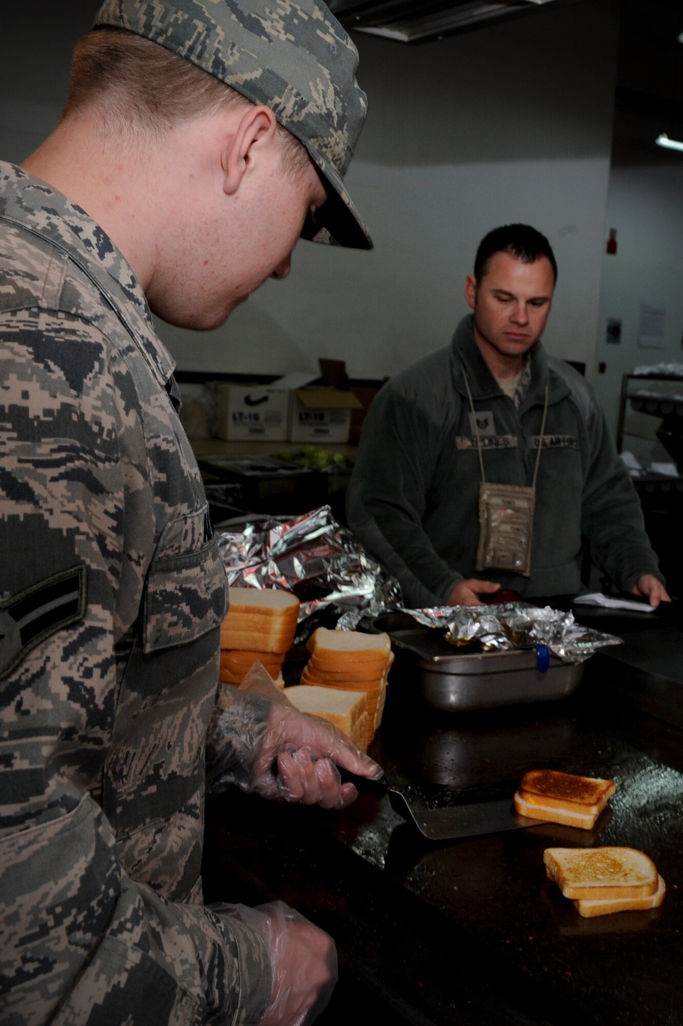 Airman 1st Class Nicholas Altice, 332nd Expeditionary Force Support Squadron, prepares grilled cheese sandwiches in the Huntley Dining Facility at an undisclosed location in Southwest Asia, Jan. 21, 2012. Altice and fellow dining facility staff prepare and serve food alongside local nationals to feed the base populace. Altice is deployed from Joint Base Langley-Eustis, Va., and is a native of Roanoke, Va. (U.S. Air Force photo by Staff Sgt. Joshua J. Garcia/Released)