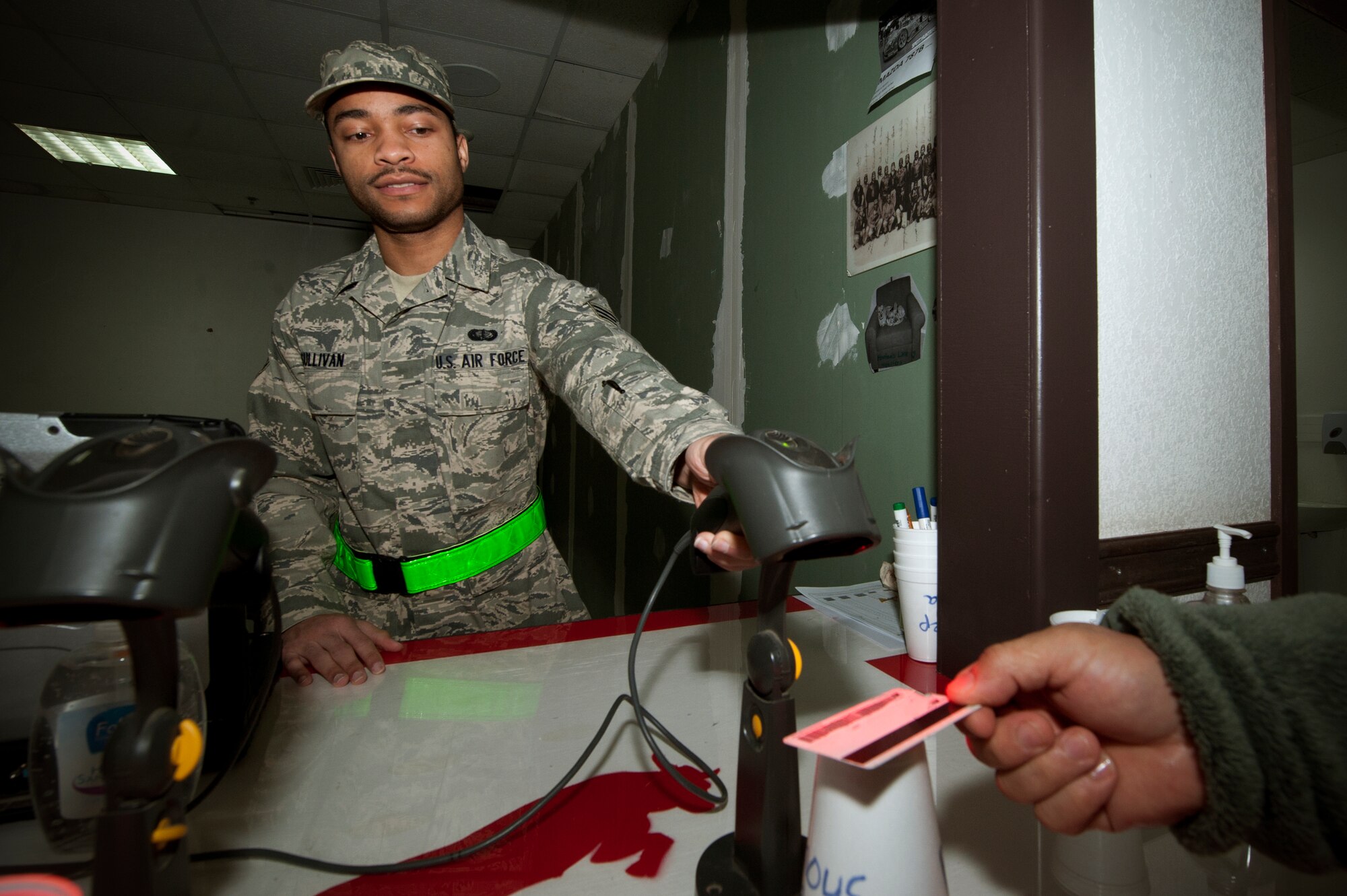 Senior Airman Aldolfo Sullivan, 332nd Expeditionary Force Support Squadron, scans an identification card at the Huntley Dining Facility Jan. 21, 2012. Base personnel scan their cards to keep track of the number of people eating at each mealtime. Sullivan is deployed from Joint Base Langley-Eustis, Va., and is a native of San Antonio, Tex. (U.S. Air Force illustration by Staff Sgt. Joshua J. Garcia/Released)