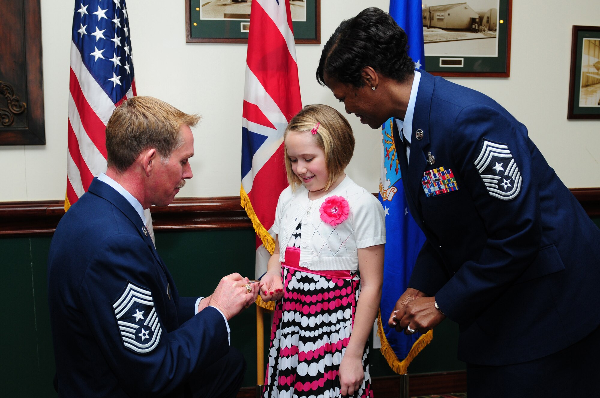 ROYAL AIR FORCE LAKENHEATH, England -- Chief Master Sgt. Christopher Powell, 100th Air Refueling Wing command chief, and Chief Master Sgt. SaRita Lathan, 48th Fighter Wing command chief, present coins to Olivia Jones, 10, for reciting her essay during the Martin Luther King Jr. luncheon, Jan. 20, 2012. Jones' essay won first place for the "Who was Martin Luther King Jr.?" contest sponsored by the Martin Luther King Jr. Committee at RAF Lakenheath. The luncheon also consisted of musical entertainment and a traditional southern buffet to commemorate King's birthday. (U.S. Air Force photo by Senior Airman Lausanne Morgan)
