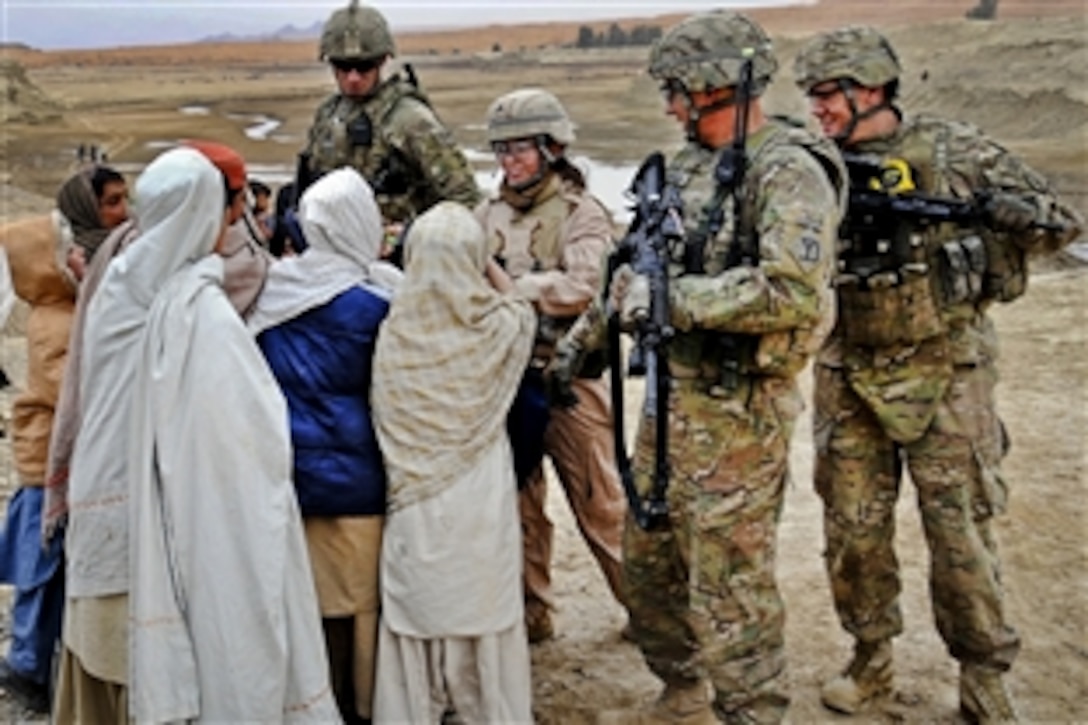 U.S. soldiers hand out pens to Afghan children during a site assessment at the Dowry Rud Check Dam in the Spin Boldak district of Kandahar province, Afghanistan, Jan. 21, 2012. The soldiers are assigned to the Kandahar Provincial Reconstruction Team security force and are deployed from the Rhode Island National Guard Company A, 1st Battalion of the 182nd Infantry Regiment. 
