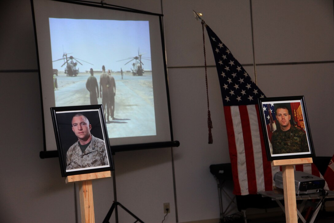 A slideshow with photos of the fallen is displayed behind photos of Capt. Daniel B. Bartle, left, and Capt. Nathan R. McHone at a memorial ceremony at Camp Bastion, Afghanistan, Jan. 24. Bartle, a native of Ferndale, Wash.; and McHone, from Crystal Lake, Ill.; were among six Marines with Marine Heavy Helicopter Squadron 363 who died when their CH-53D Sea Stallion helicopter crashed conducting combat operations in Helmand province, Afghanistan, Jan. 19. While the crash is currently under investigation, NATO officials said there were no signs of enemy activity in the area at the time of the incident. “It is difficult to be here, easier to suppress our emotions and move on with our daily routine,” said Lt. Col. Mark Revor, commanding officer of Marine Heavy Helicopter Squadron 363, in his remarks at the ceremony. “It is difficult because they were more than friends, more than family – they were our brothers and our comrades.”