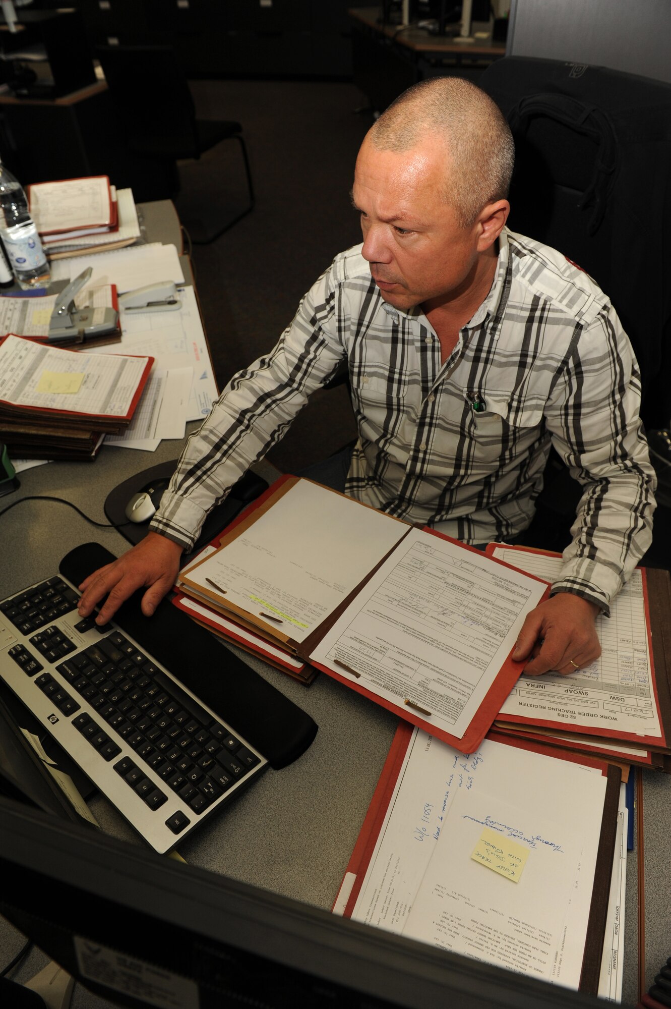 SPANGDAHLEM AIR BASE, Germany – Roland Monschauer, 52nd Civil Engineer Squadron customer service scheduler, organizes and schedules work-order requests at the CES customer service desk at Bldg. 120 here Jan. 19. CES processes and organizes more than 1,100 work orders a month requesting base maintenance, repairs and construction to be fulfilled by the 52nd CES and local contractors. (U.S. Air Force photo/Airman 1st Class Matthew B. Fredericks)