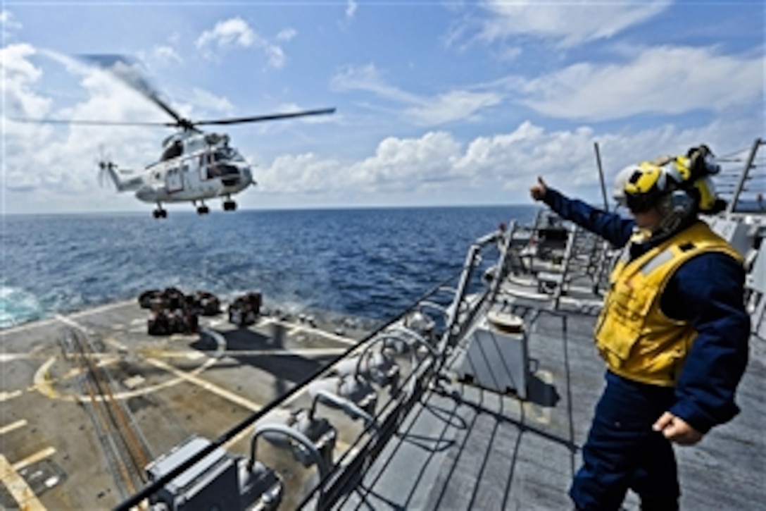 U.S. Navy Petty Officer 3rd Class Kristin Butts signals the pilot an AS-332 Super Puma helicopter during a vertical replenishment mission aboard the guided-missile destroyer USS Dewey during a vertical replenishment mission with the Military Sealift Command dry cargo and ammunition ship USNS Washington Chambers under way in the Indian Ocean, Jan. 24, 2012. Butts is a boatswain's mate. The Dewey is deployed to the U.S. 7th Fleet area of responsibility conducting maritime security operations.