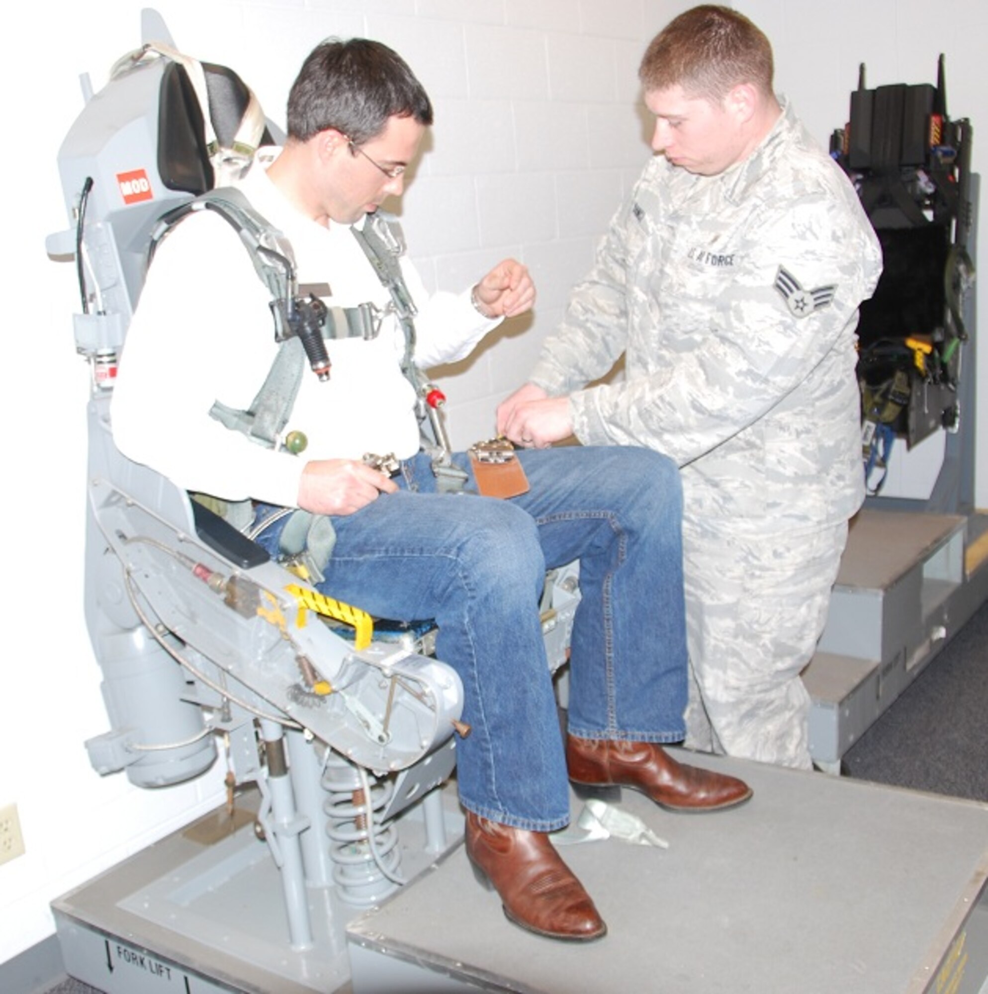 David Cartwright, Leadership Wichita Falls 2012 class member, gets an assist from Aerospace Physiology technician Senior Airman Ryan Dancz strapping into the mock ejection seat during a Sheppard base tour Jan 24, 2012. (U.S. Air Force photo/Debi Smith)