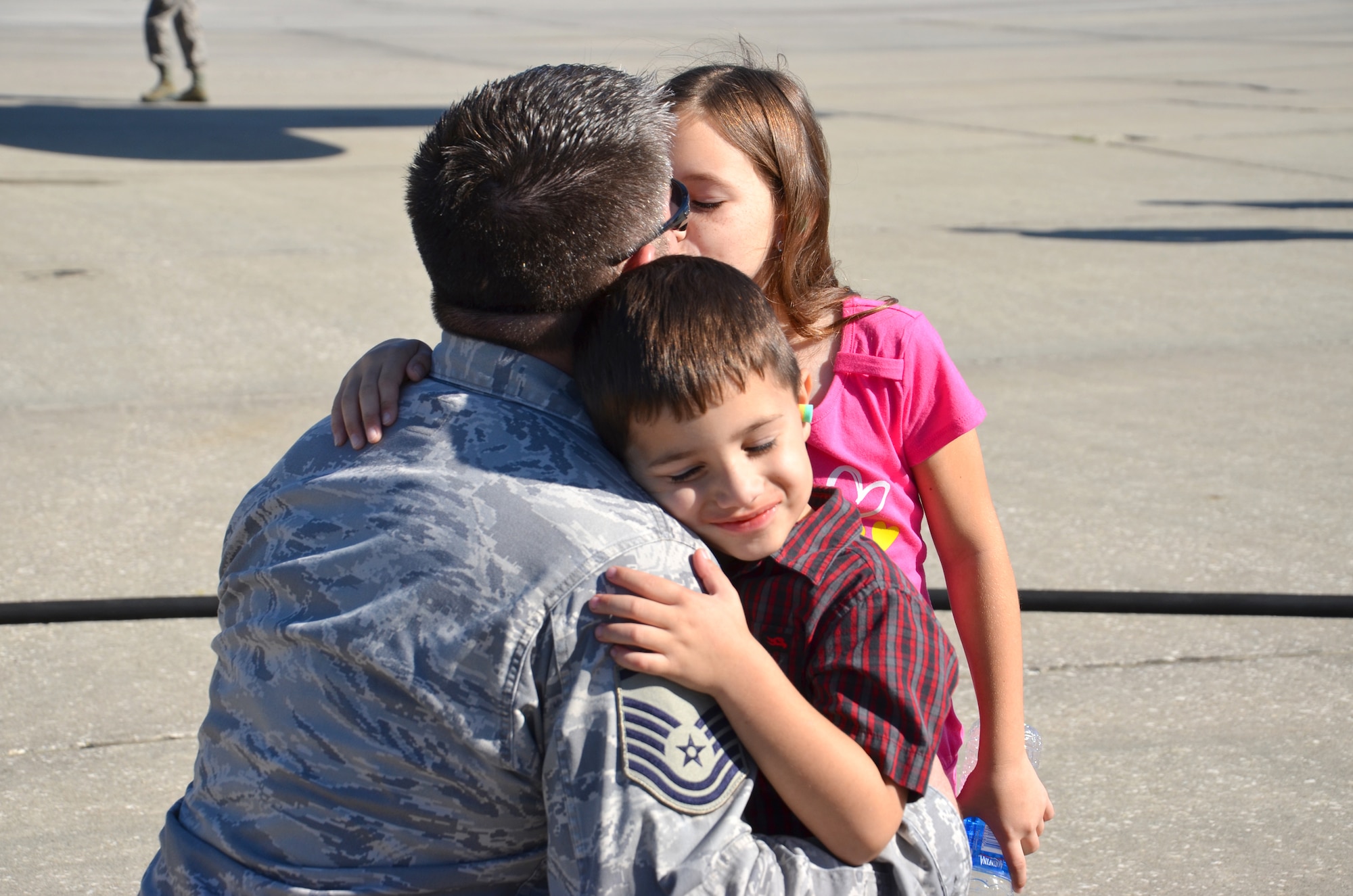 Master Sgt. Joel Lindsey, electronic integrated systems supervisor, 920th Rescue Wing, Patrick Air Force Base, Fla., gives his daughter and son a hug and kiss Jan 25. Lindsey is one of approximately 60 Rescue Airmen deploying to the Horn of Africa for 120 days to support the ongoing search and rescue and humanitarian relief efforts there. (U.S. Air Force photo/Senior Airmen Natasha Dowridge)