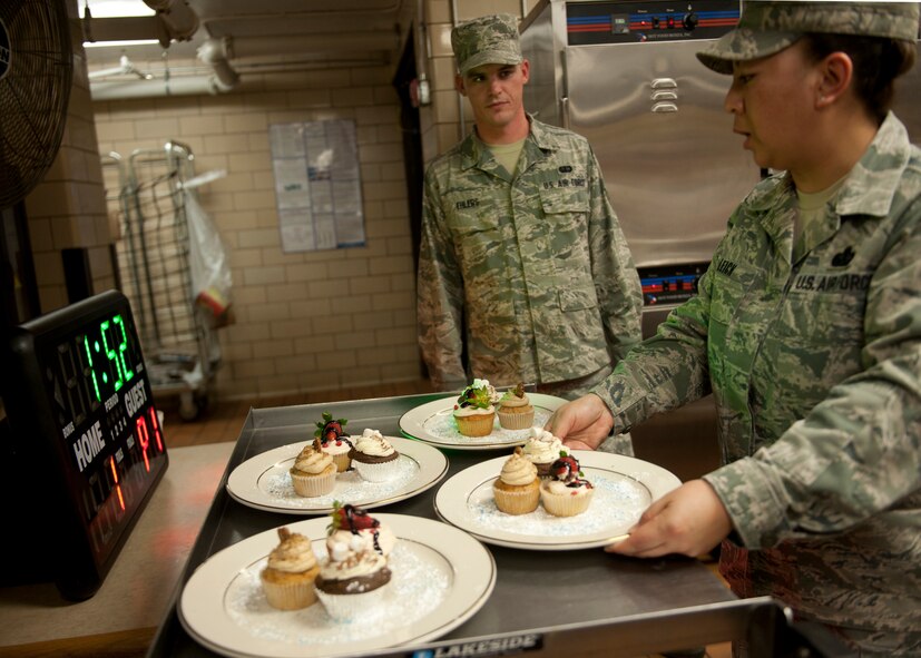 U.S. Air Force Senior Airman Robert Ehlers and Master Sgt. Shiela Leick, both from the 23d Force Support Squadron, begin placing finished cupcakes on a cart to be brought to the judges during the Cupcake Wars event held at the Georgia Pines Dining Facility Jan. 24, 2012, at Moody Air Force Base, Ga. Like the recent Iron Chef competition, the dining facility hopes to continue holding Cupcake Wars events featuring participants from various units on base. (U.S. Air Force photo by Senior Airman Eileen Meier/Released)