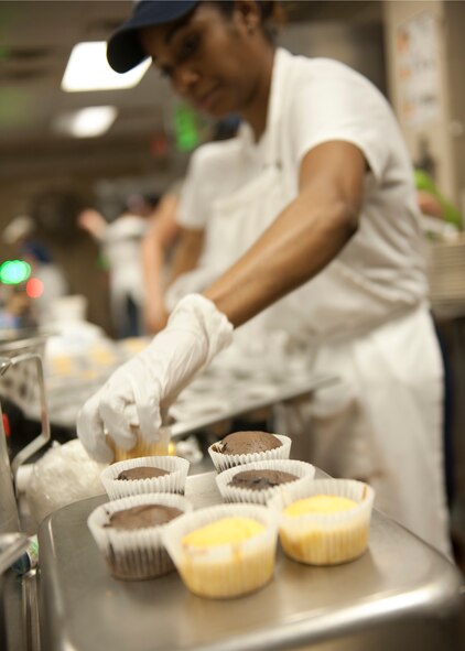 Tanica Case of team “Shorties” removes freshly-baked cupcakes from a pan during the Cupcake Wars held at the Georgia Pines Dining Facility at Moody Air Force Base, Ga., Jan. 24, 2012. The winter wonderland themed event was the first of its kind at Moody and was geared to boost morale within the dining facility. (U.S. Air Force photo by Senior Airman Eileen Meier/Released)
