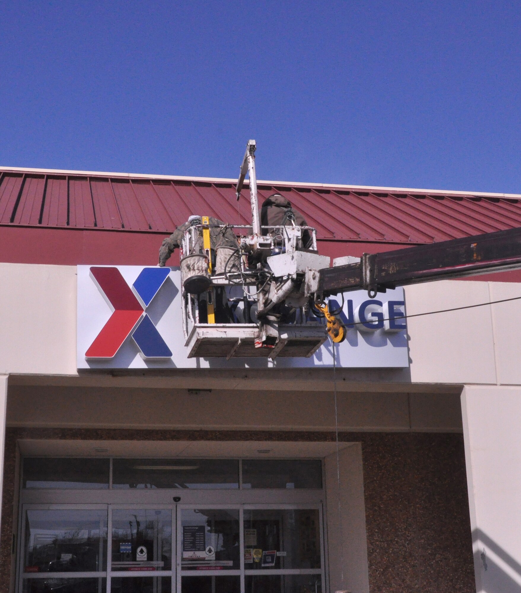 Eric Bailey and Steve Smith with General Lighting and Sign Services in Oklahoma City, Okla., install a new sign for the Exchange at Vance Air Force Base, Okla., Jan. 23.  The Army & Air Force Exchange Service, serving America’s armed forces for more than 115 years, has traded in the old name, “base exchange,” and is now simply, “Exchange.”  The new sign is part of that image change, said Bill Fichtler, the Vance Air Force Base Exchange manager. (U.S. Air Force photo/ Airman 1st Class Frank John Casciotta)
