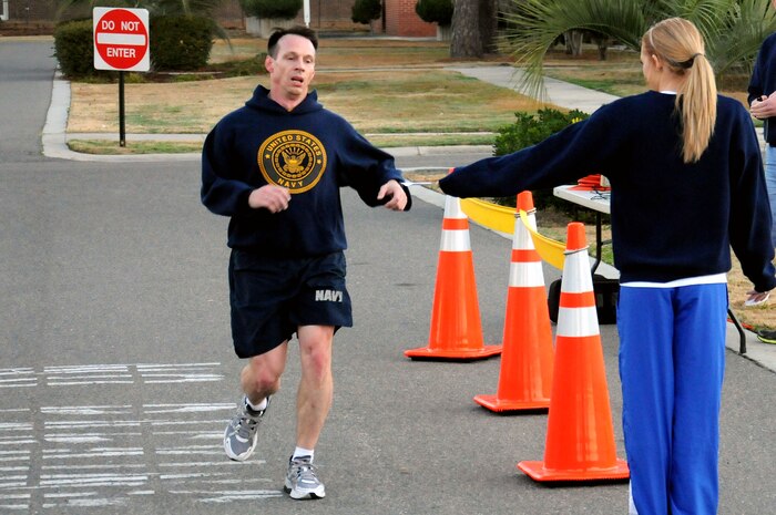 Master Chief Petty Officer Billy Cady is given his place card from Edie Foley for finishing first during the Road Rage challenge at Joint Base Charleston - Weapons Station, Jan. 25.  Cady finished with a time of 24:01 in the five kilometer race that is sponsored by Morale, Welfare and Recreation. Cady is the  Joint Base Charleston – Weapons Station command master chief and Foley is an MWR fitness trainer and event coordinator. (U.S. Navy photo/Petty Officer 2nd Class Brannon Deugan)