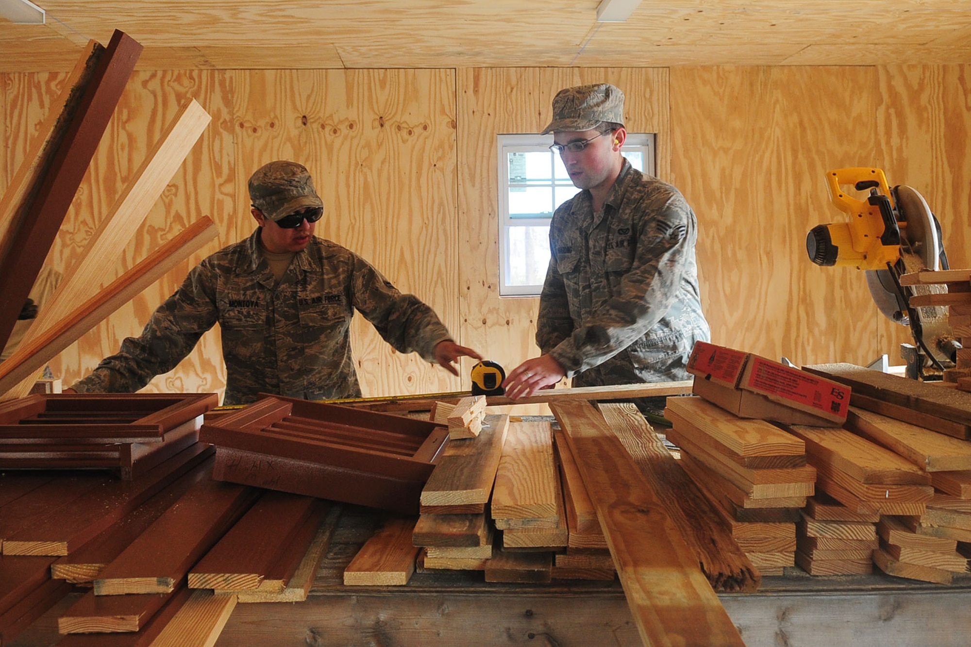 U.S. Air Force Airman 1st Class Oscar Montoya, 633rd Civil Engineer Squadron structuralist, assists Senior Airman Joshua Harding with sawing wood at Langley Air Force Base Va., Jan. 24, 2012. Nearly everyone from the 633rd CES played a role in constructing the new Raptor Town. (U.S. Air Force photo by Staff Sgt. Ashley Hawkins/Released)